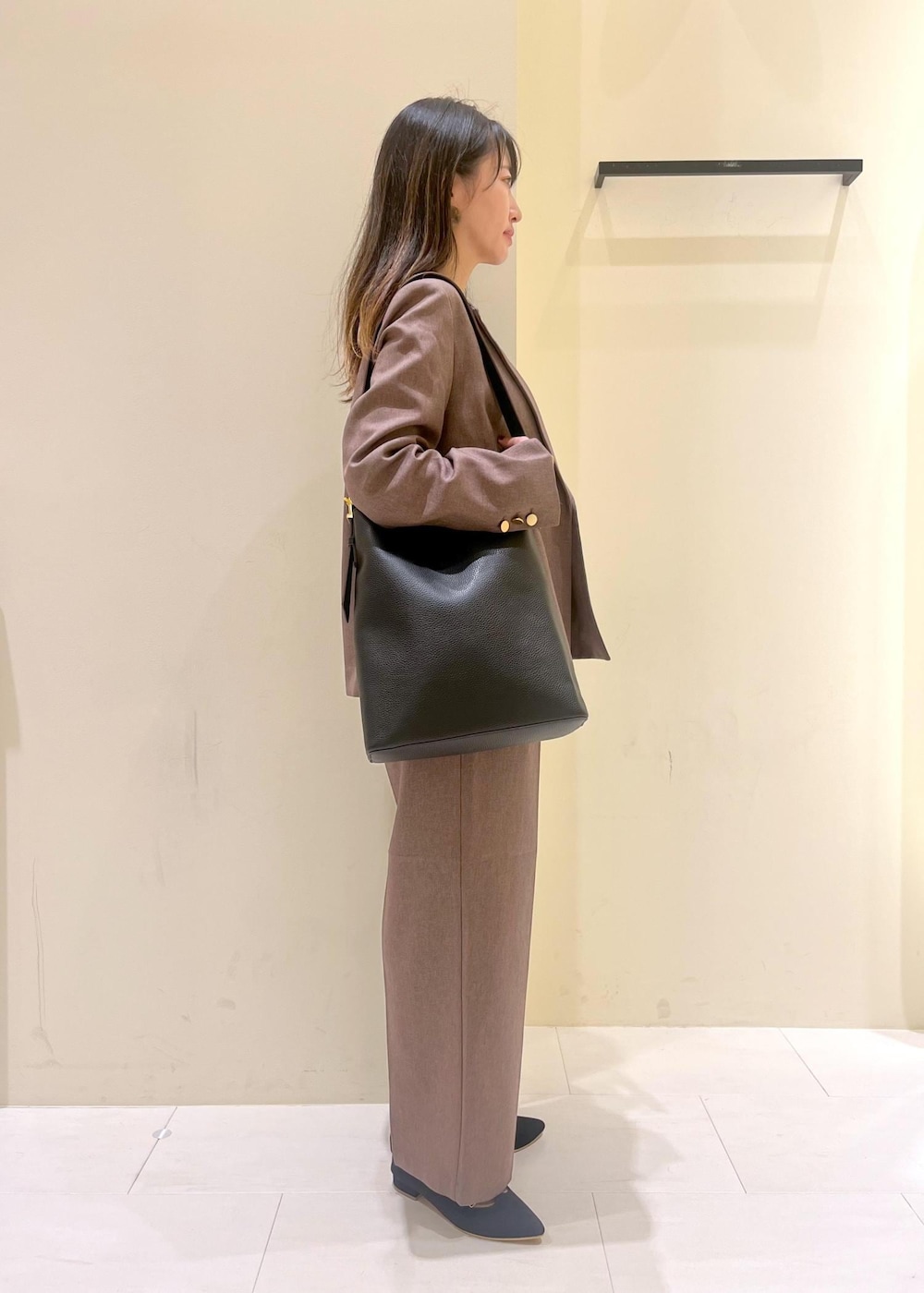 ブラック系のショルダーバッグ、ブラック系のシャツ/ブラウス、ベージュ系のテーラードジャケットを着用したレディースの秋コーディネートの2枚目の写真