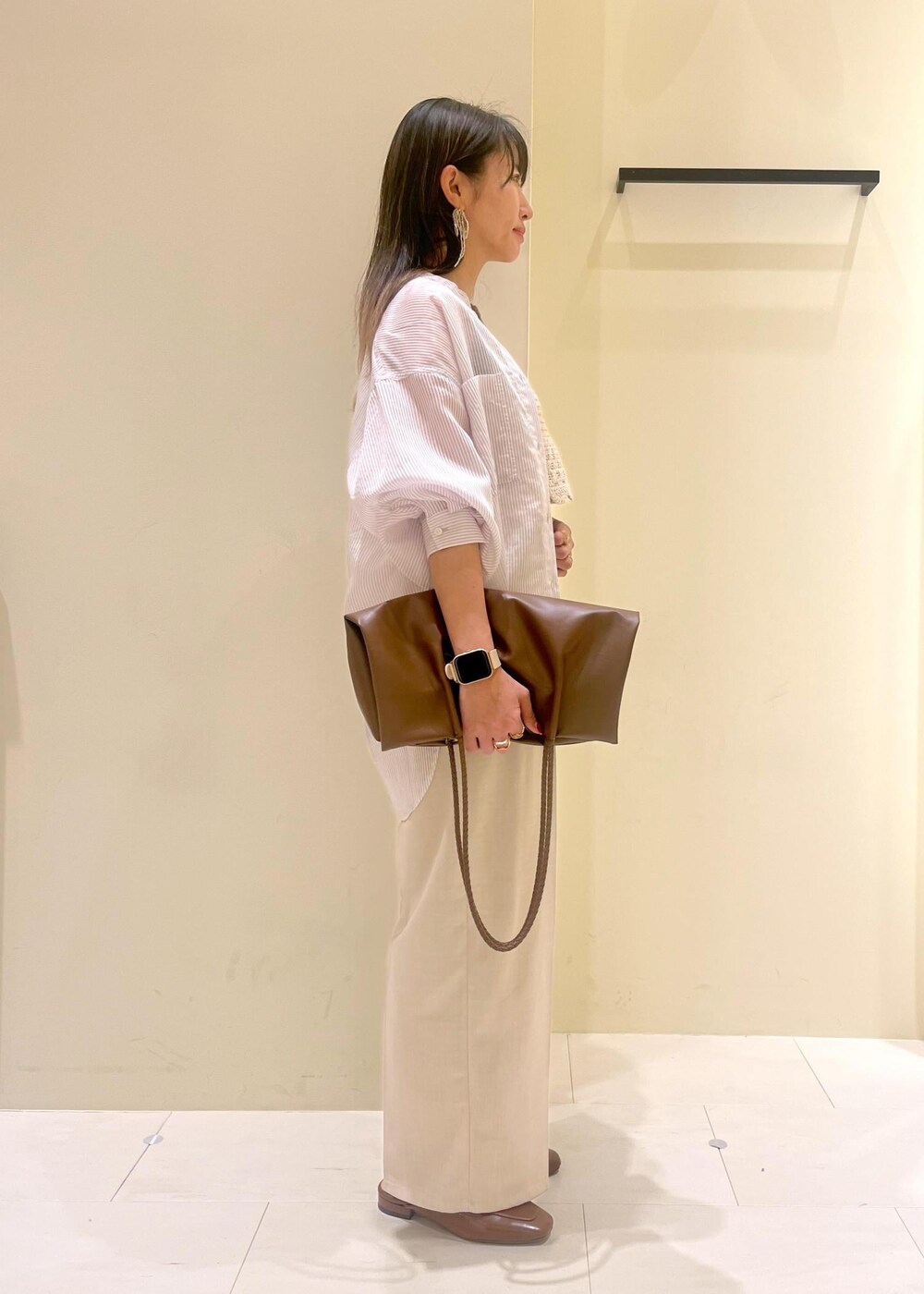 ブラック系のタンクトップ、ブラウン系のトートバッグ、イエロー系のローファーを着用したレディースの春コーディネートの4枚目の写真