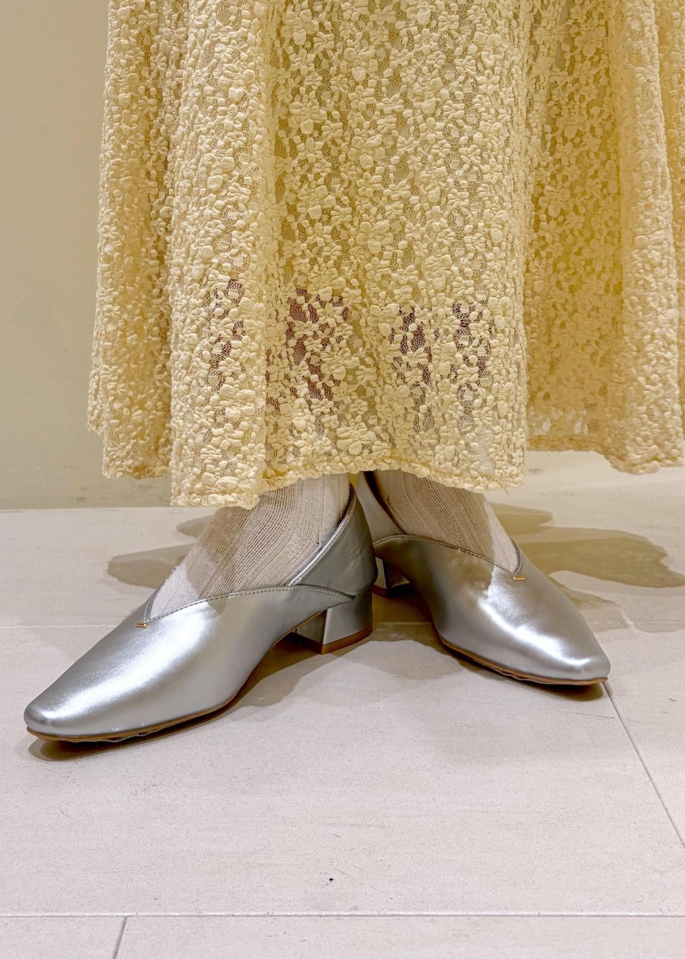 ホワイト系のボストンバッグ、ベージュ系のスカート、ブラウン系のカーディガン/ボレロを着用したレディースの春コーディネートの9枚目の写真