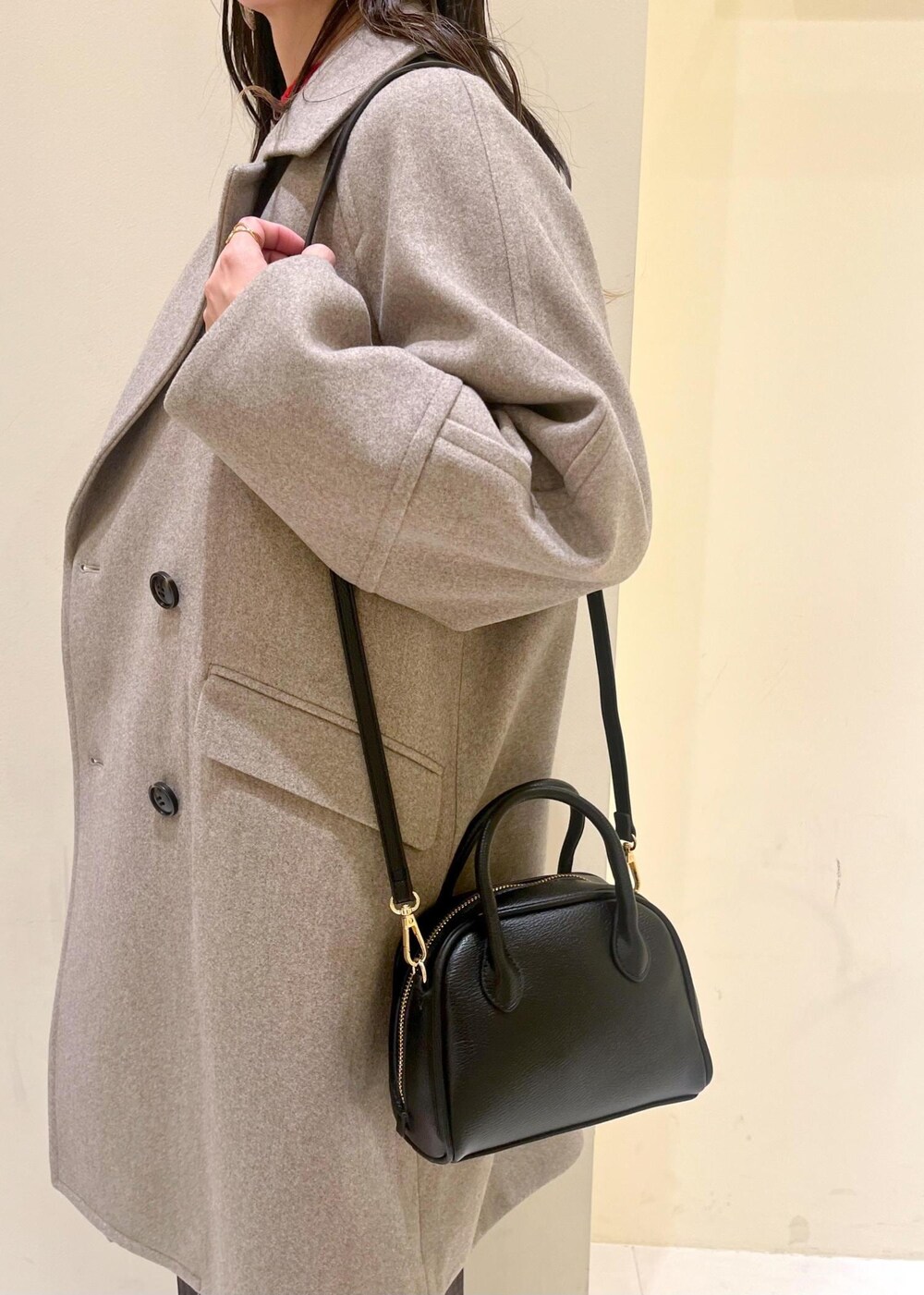 ブラック系のショルダーバッグ、レッド系のニット/セーター、ブラウン系のピーコートを着用したレディースの秋コーディネートの7枚目の写真