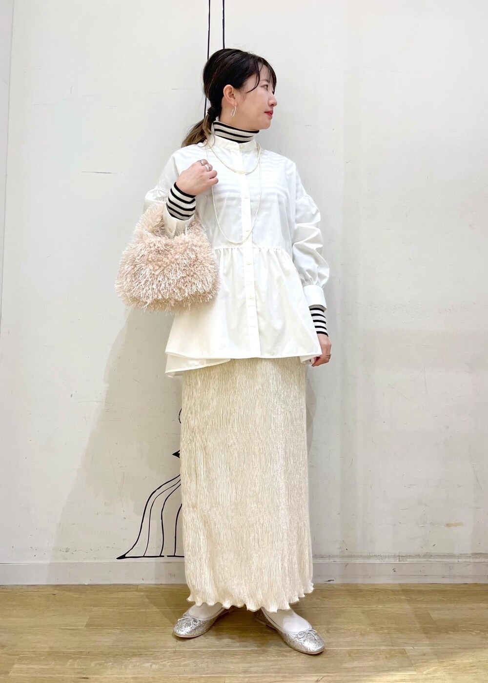 ベージュ系のハンドバッグ、ホワイト系のニット/セーター、シルバー系のバレエシューズを着用したレディースの冬コーディネートの2枚目の写真