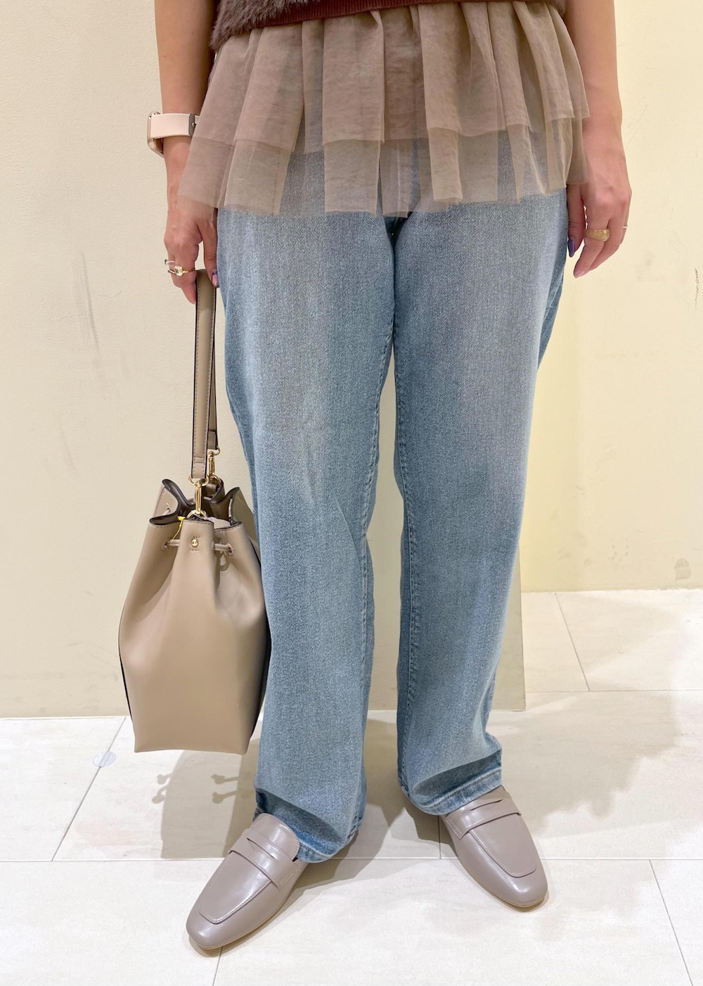 グレー系のローファー、ブルー系のデニムパンツ、ベージュ系のショルダーバッグを着用したレディースの夏コーディネートの9枚目の写真