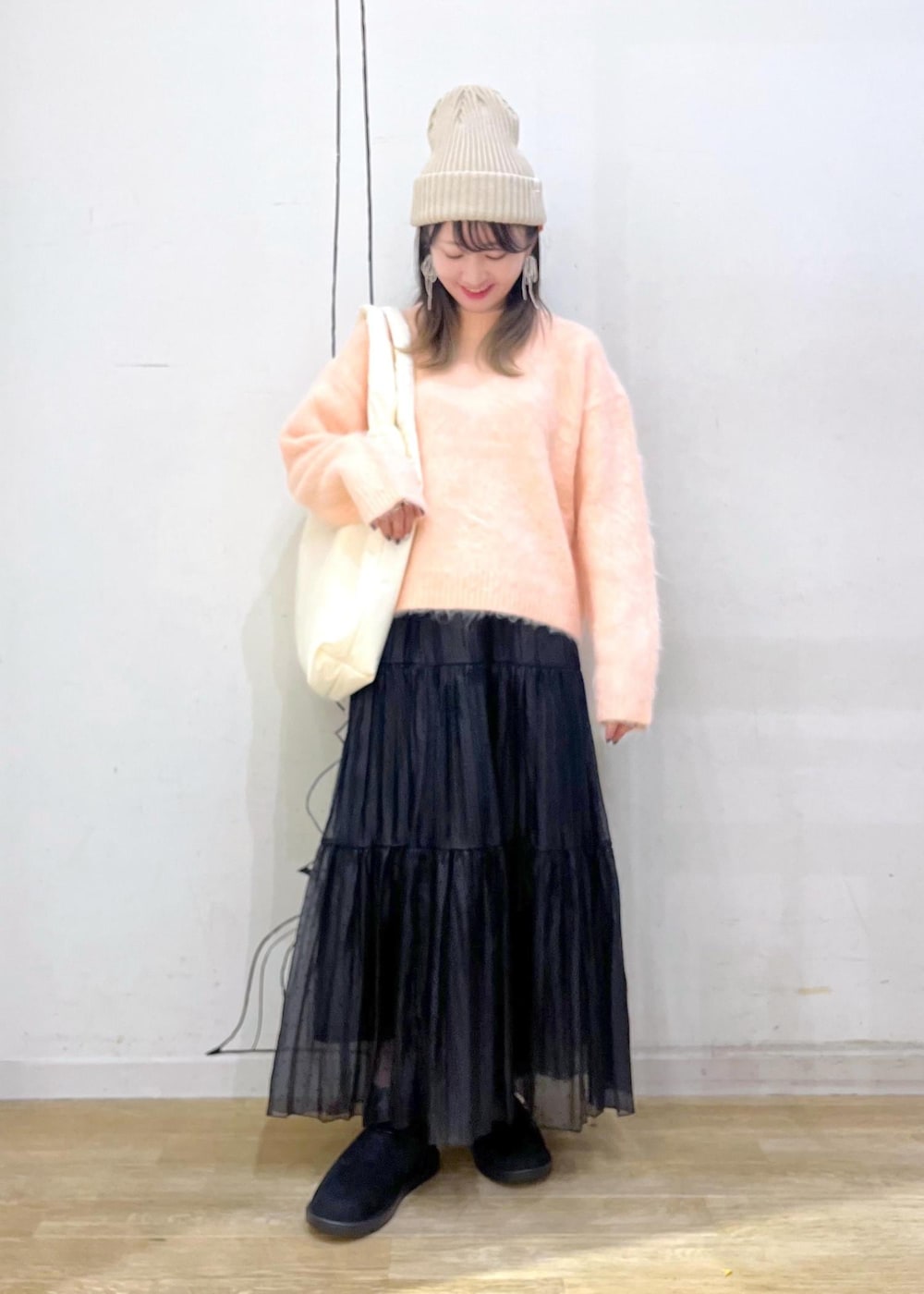 ホワイト系のトートバッグ、ピンク系のニット/セーター、ブラック系のスカートを着用したレディースの冬コーディネートの2枚目の写真