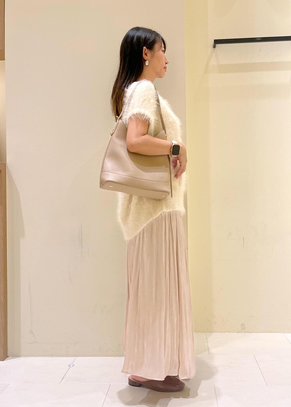 イエロー系のローファー、ベージュ系のスカート、ベージュ系のショルダーバッグを着用したレディースの夏コーディネートの3枚目の写真