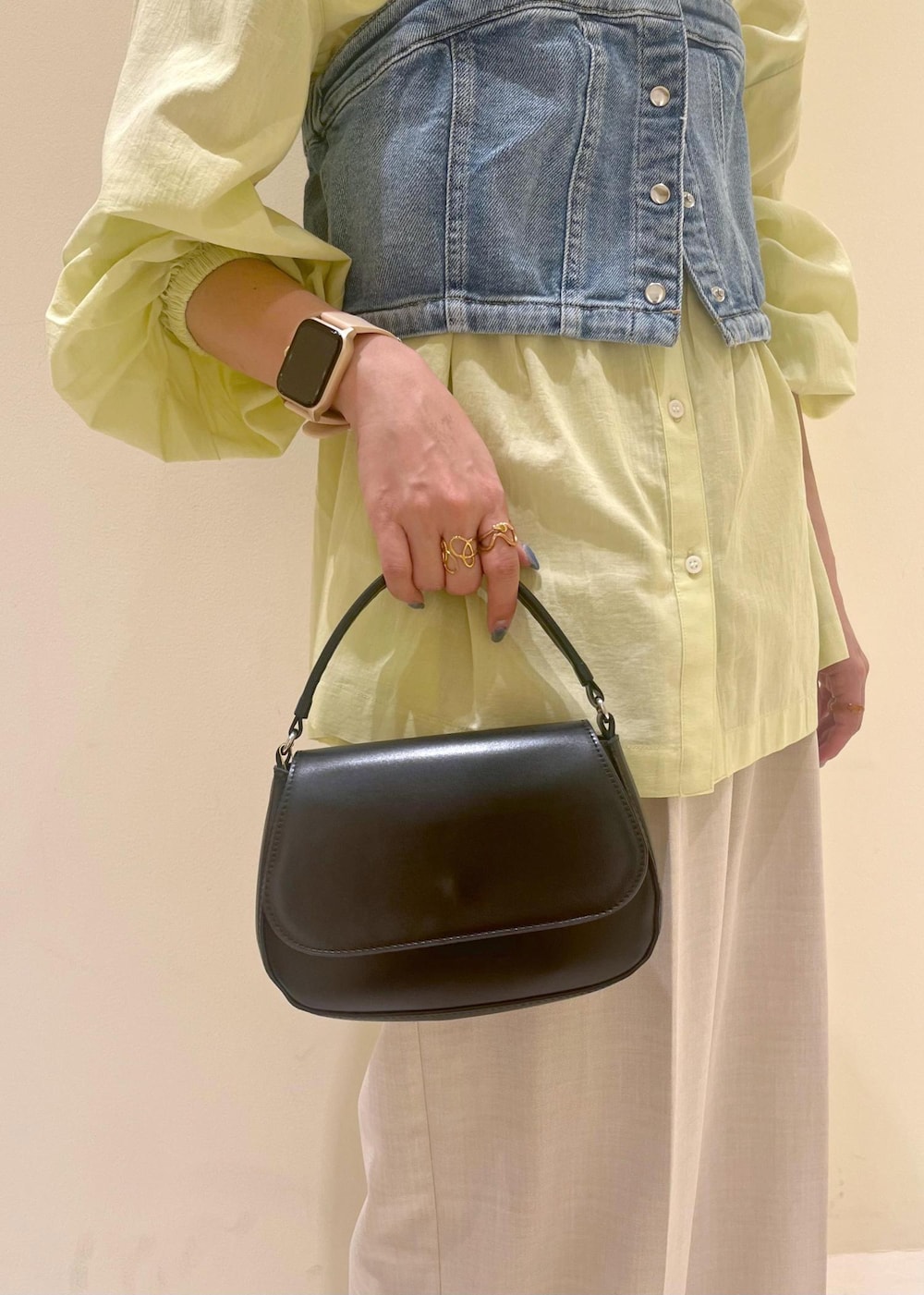 ブラック系のハンドバッグ、ブルー系のベスト、イエロー系のシャツ/ブラウスを着用したレディースの春コーディネートの8枚目の写真