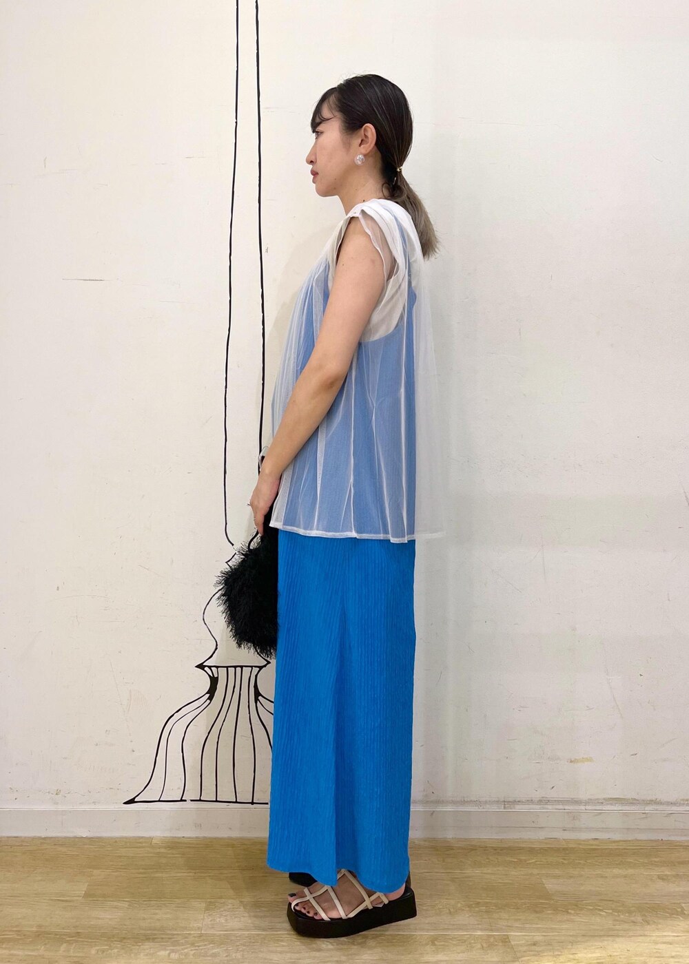 ホワイト系のサンダル、ブルー系のワンピース、ブラック系のハンドバッグを着用したレディースの夏コーディネートの2枚目の写真