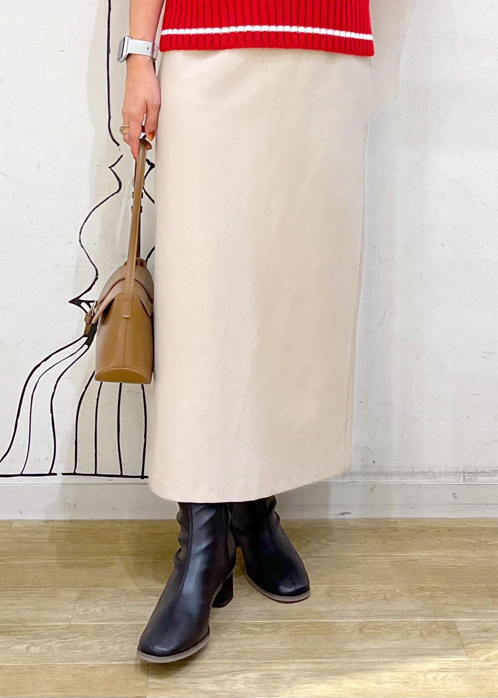 ベージュ系のスカート、レッド系のニット/セーター、ブラック系のブーツを着用したレディースの秋コーディネートの7枚目の写真