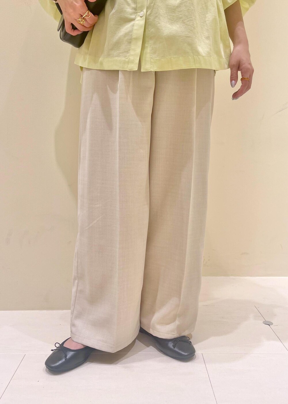 ブラック系のハンドバッグ、ブルー系のベスト、イエロー系のシャツ/ブラウスを着用したレディースの春コーディネートの9枚目の写真