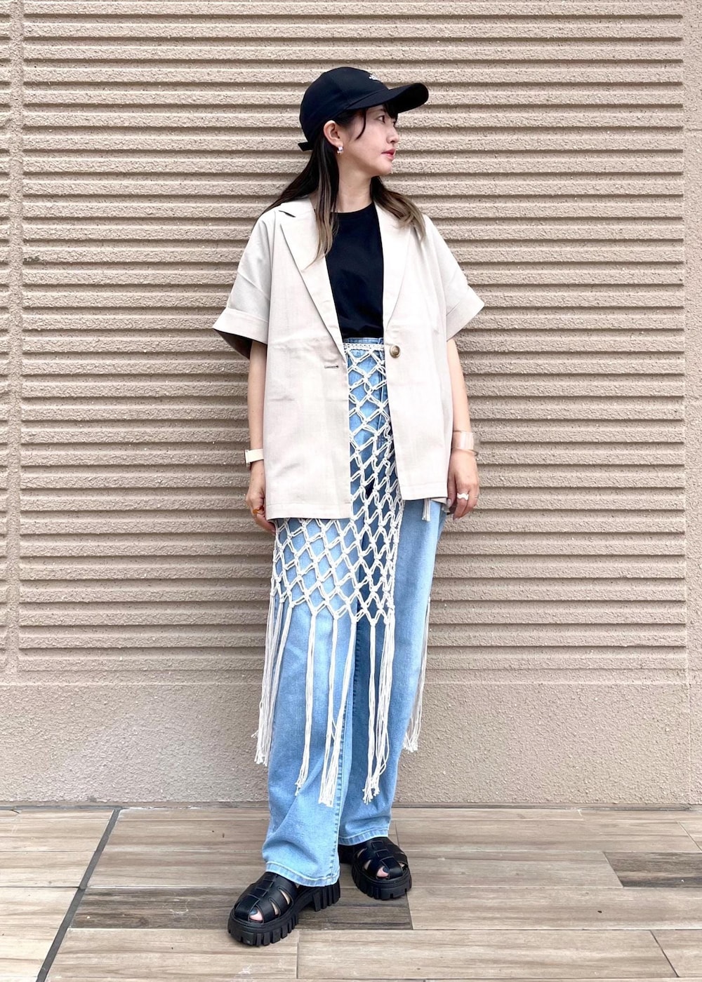 ブルー系のデニムパンツ、ホワイト系のスカート、ブラック系のTシャツ/カットソーを着用したレディースの春コーディネートの2枚目の写真