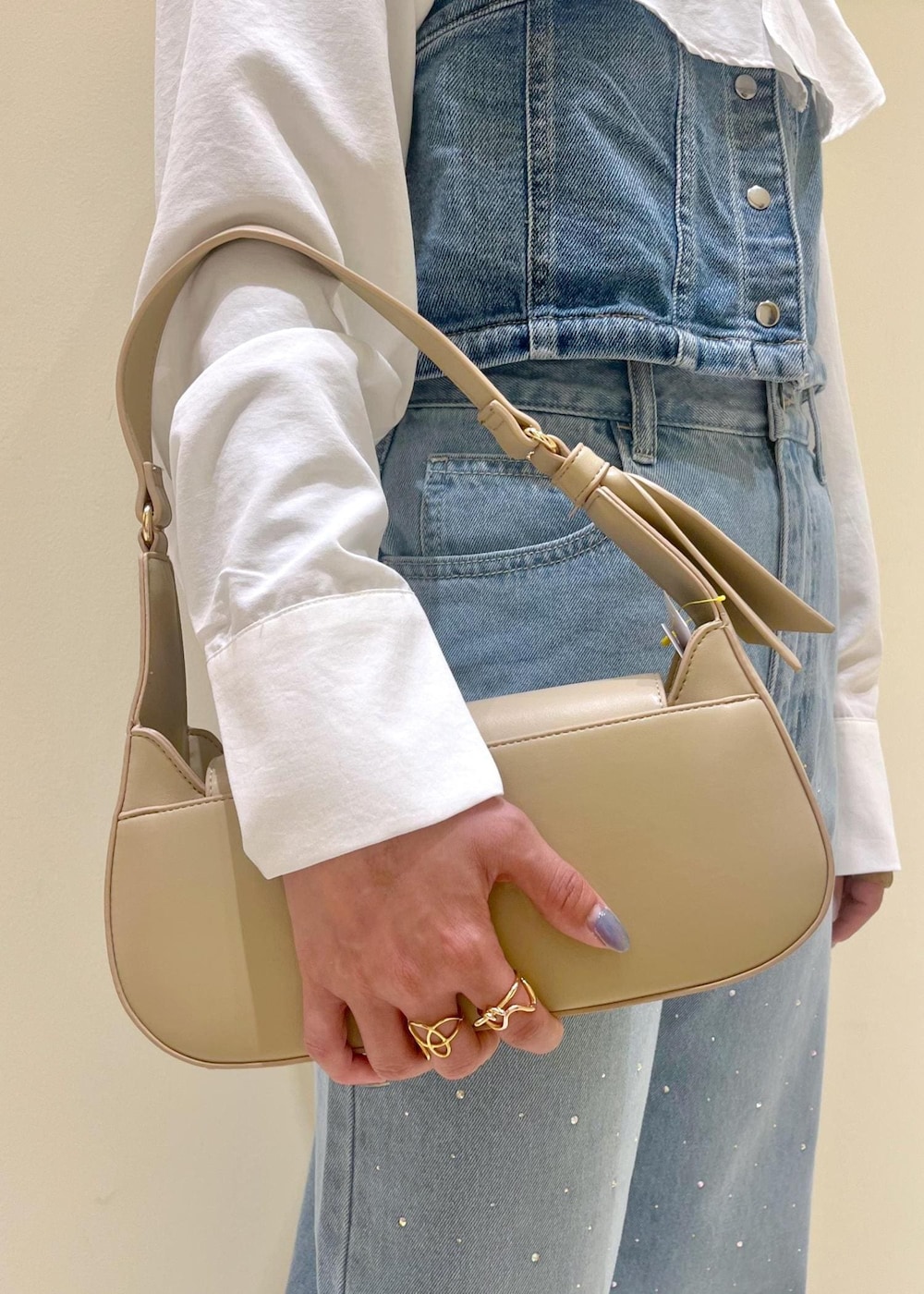 ベージュ系のハンドバッグ、ブルー系のデニムパンツ、ブルー系のベストを着用したレディースの春コーディネートの7枚目の写真