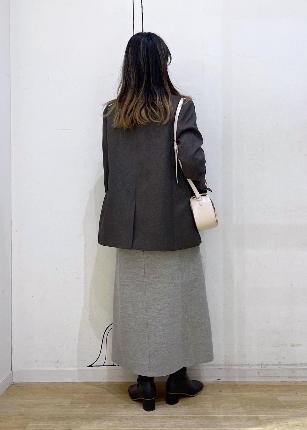 ホワイト系のショルダーバッグ、ブラック系のブーツ、ホワイト系のニット/セーターを着用したレディースの冬コーディネートの5枚目の写真