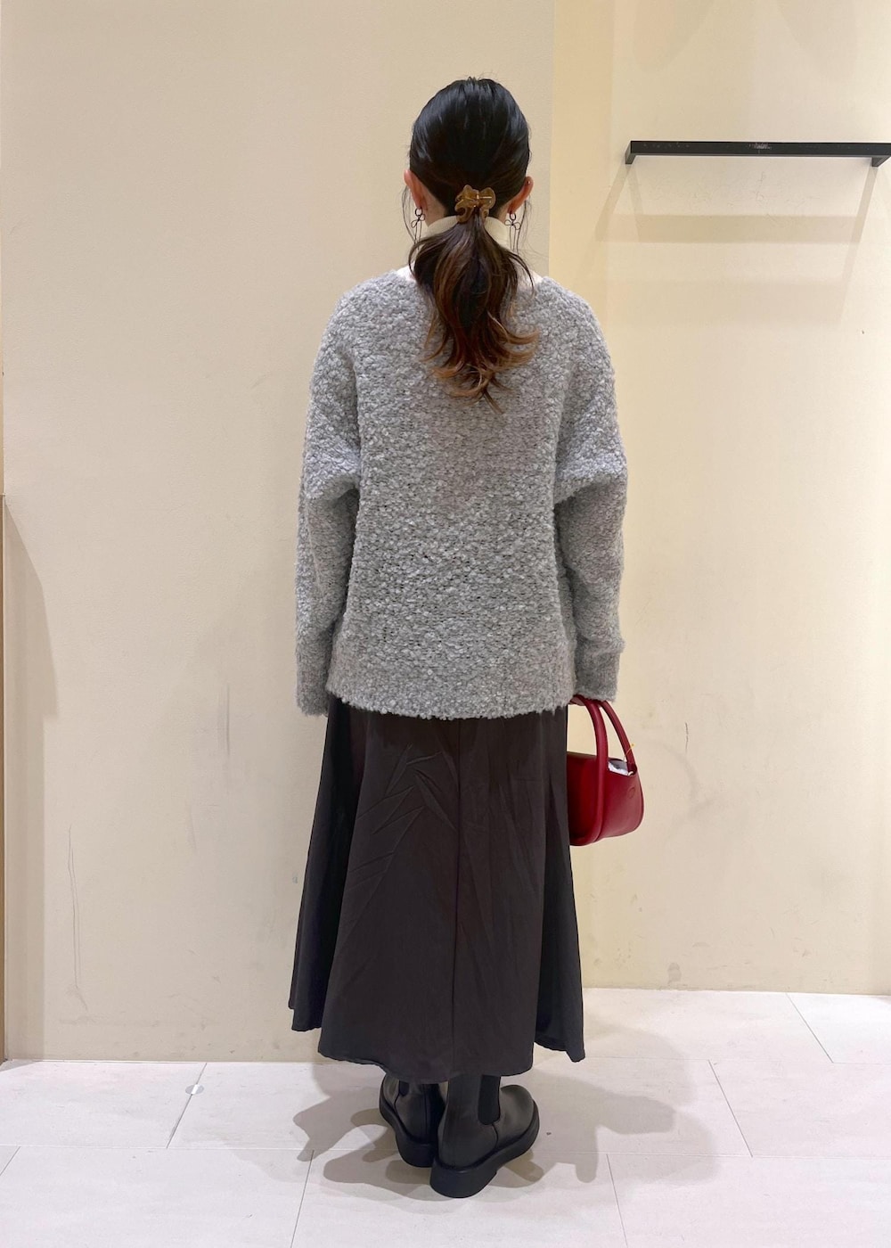 ホワイト系のニット/セーター、グレー系のスカート、レッド系のショルダーバッグを着用したレディースの冬コーディネートの4枚目の写真