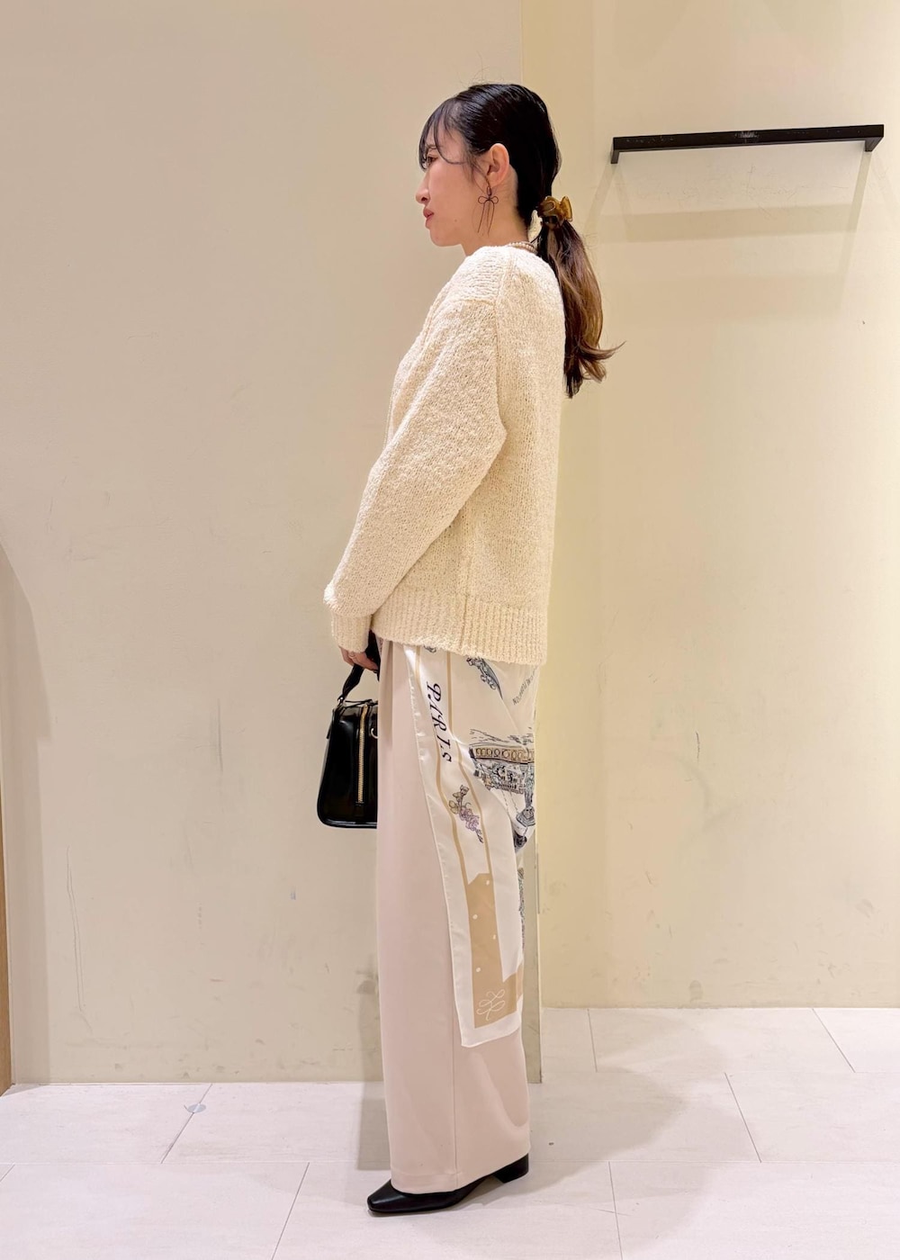 ブラック系のボストンバッグ、ベージュ系のその他パンツ、ホワイト系のニット/セーターを着用したレディースの冬コーディネートの4枚目の写真