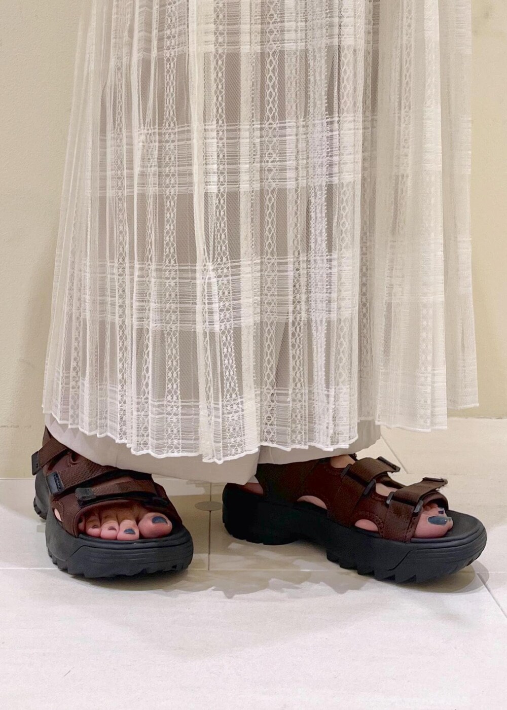 イエロー系のトートバッグ、ホワイト系のスカート、ベージュ系のその他パンツを着用したレディースの夏コーディネートの10枚目の写真