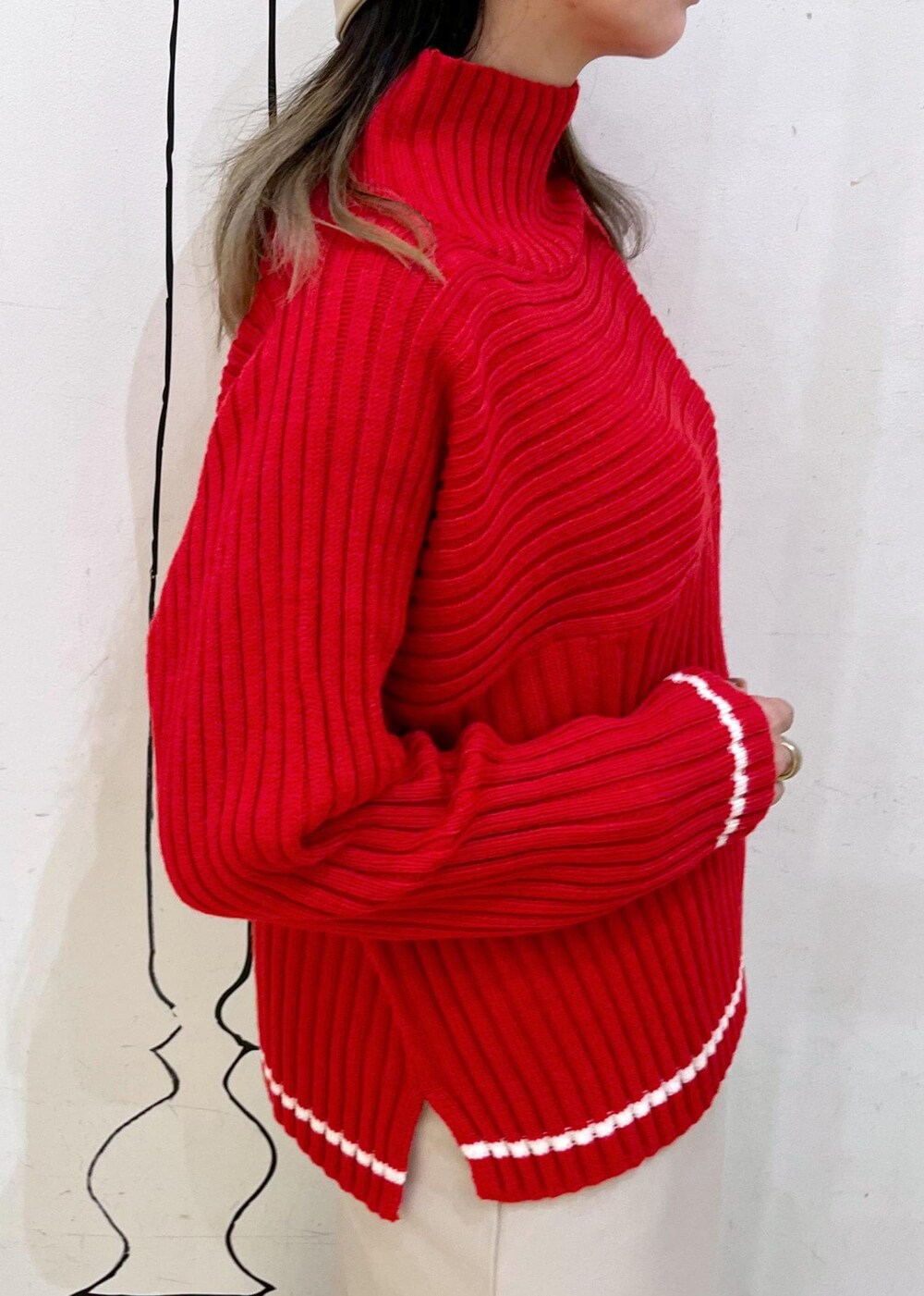 ベージュ系のスカート、レッド系のニット/セーター、ブラック系のブーツを着用したレディースの秋コーディネートの6枚目の写真