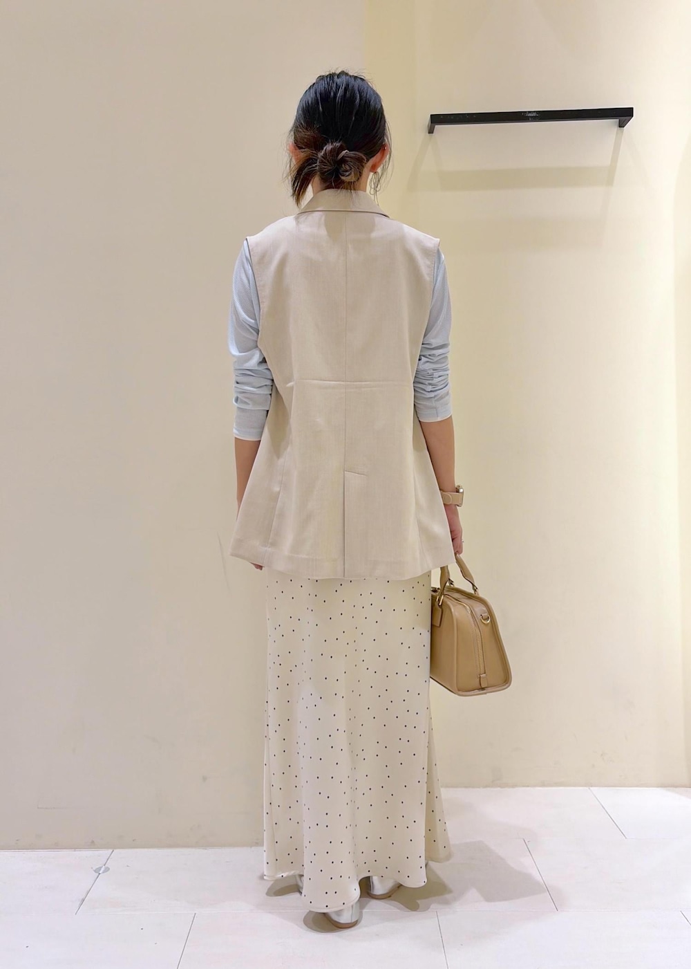 ベージュ系のボストンバッグ、ブルー系のTシャツ/カットソー、ベージュ系のベストを着用したレディースの春コーディネートの3枚目の写真