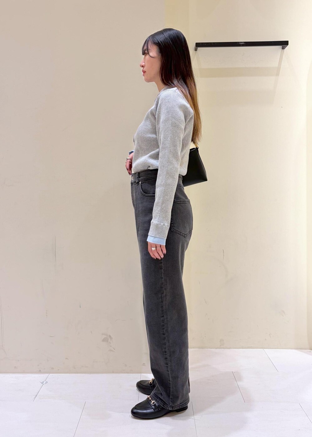 ブラック系のショルダーバッグ、ブラック系のローファー、グレー系のニット/セーターを着用したレディースの冬コーディネートの4枚目の写真