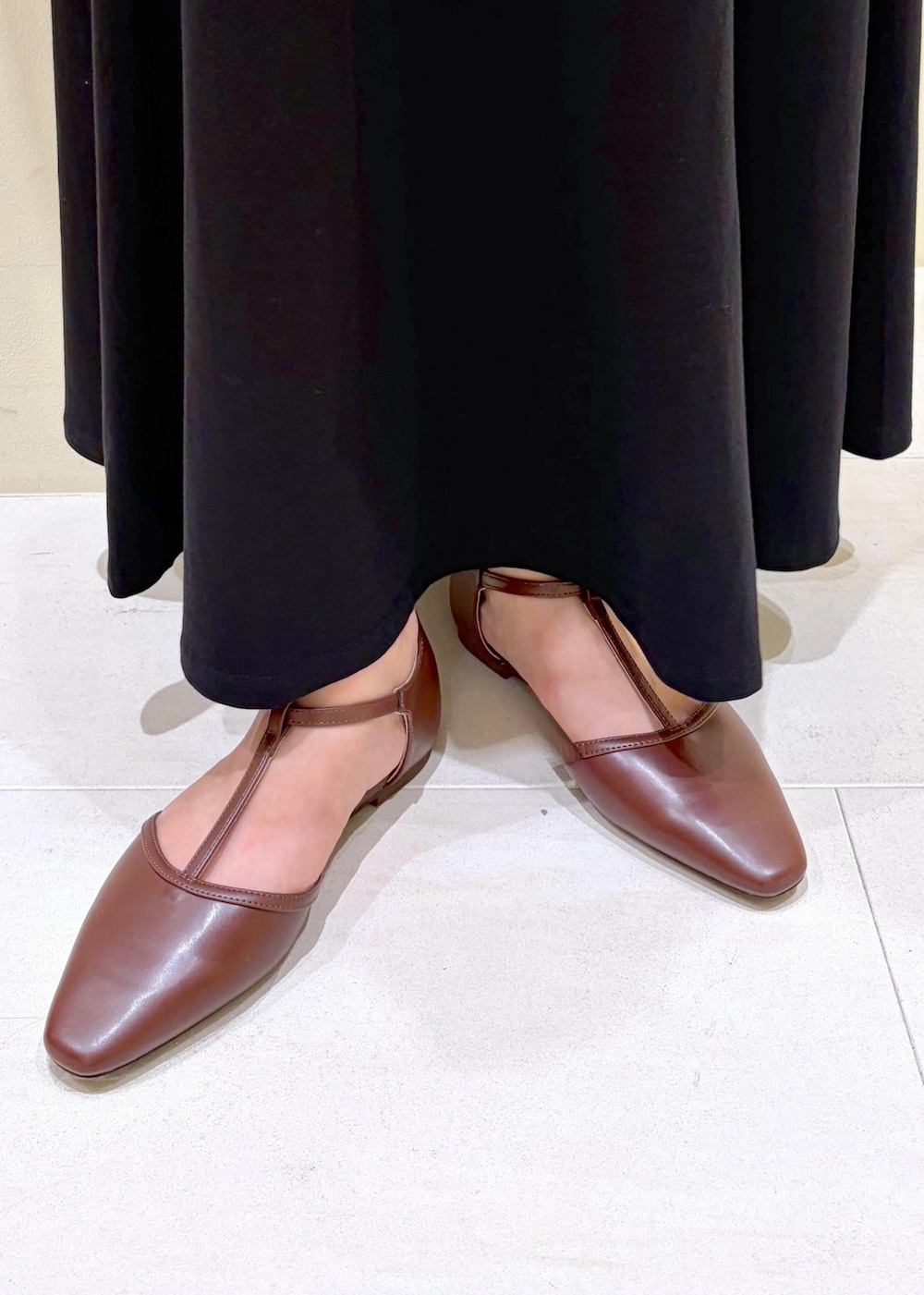 ブラック系のスカート、ホワイト系のベスト、ブラウン系のパンプスを着用したレディースの夏コーディネートの10枚目の写真