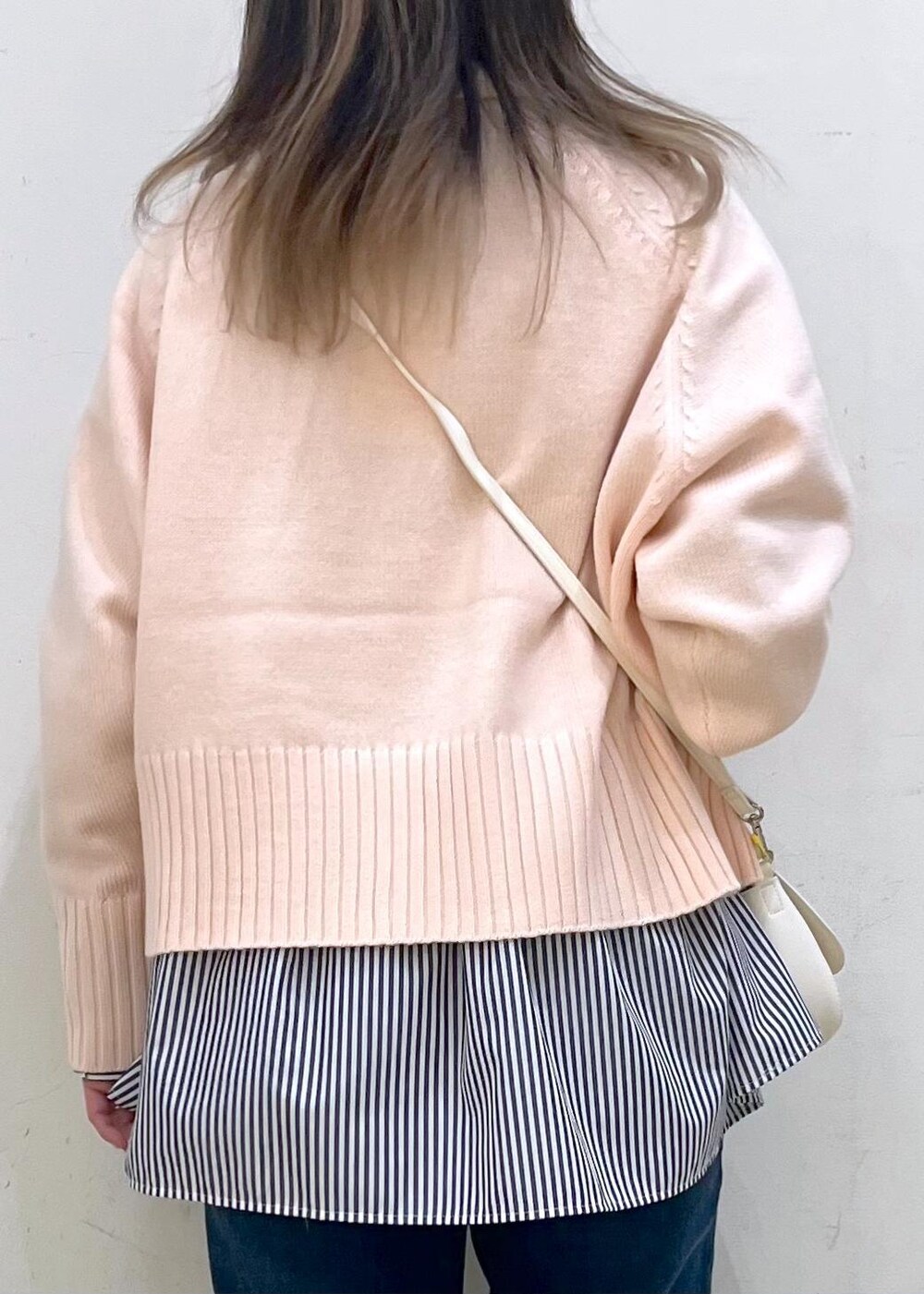 ピンク系のニット/セーター、ホワイト系のハンドバッグ、ブルー系のデニムパンツを着用したレディースの冬コーディネートの5枚目の写真