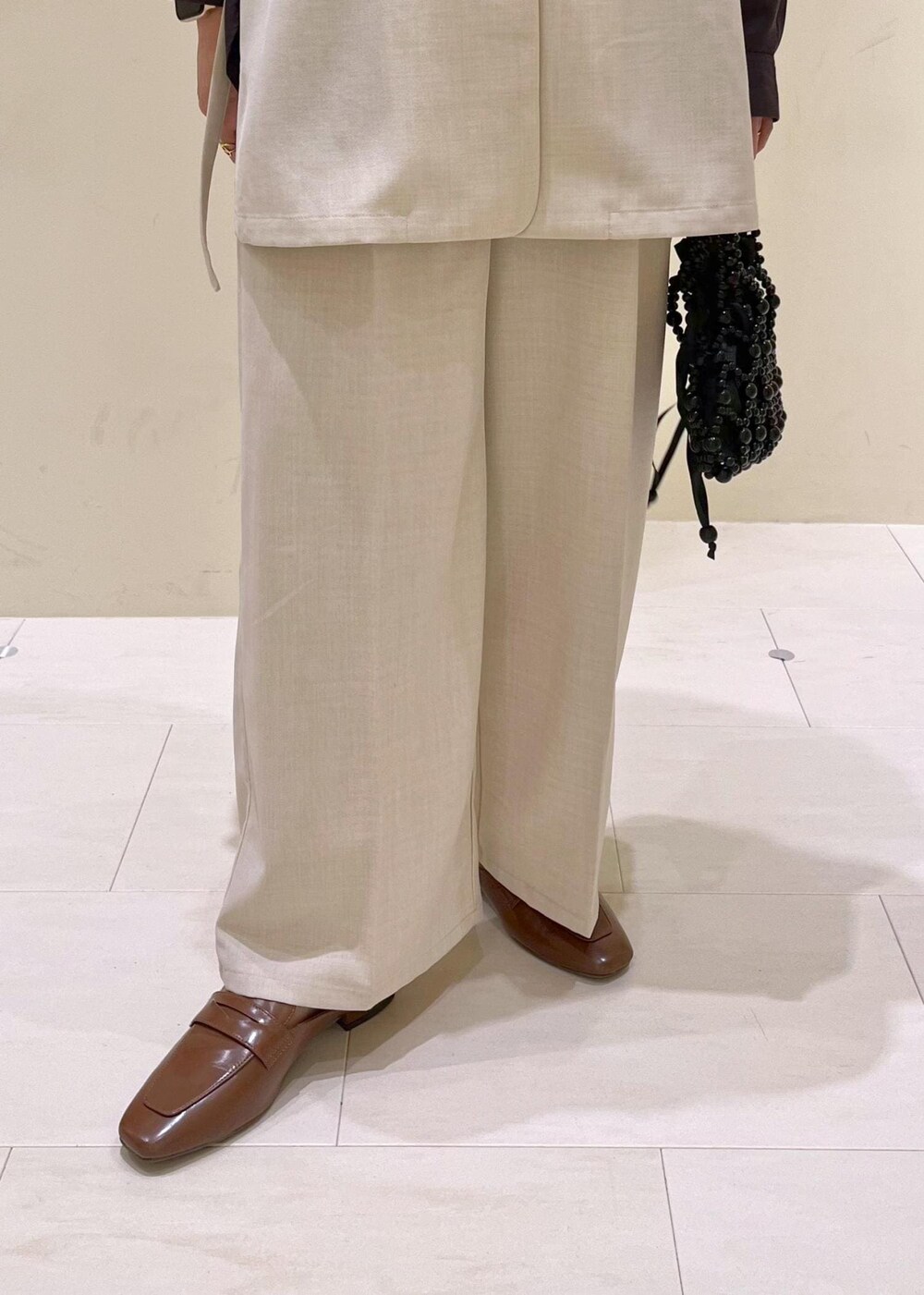 イエロー系のローファー、ブラック系のハンドバッグ、ベージュ系のベストを着用したレディースの春コーディネートの9枚目の写真