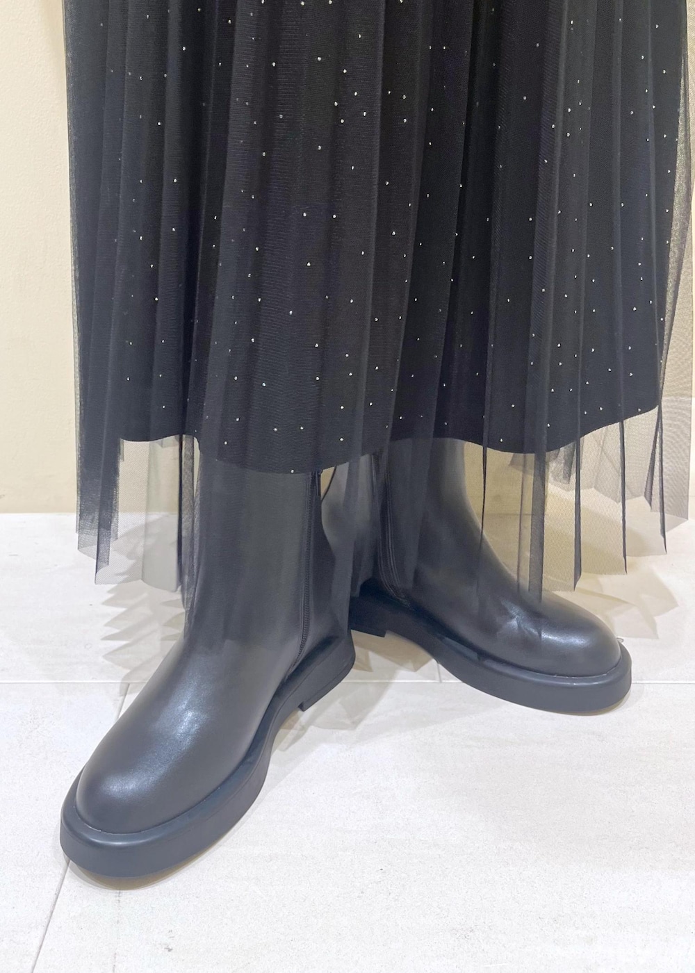 ホワイト系のショルダーバッグ、ブラック系のブーツ、ブラック系のスカートを着用したレディースの冬コーディネートの10枚目の写真