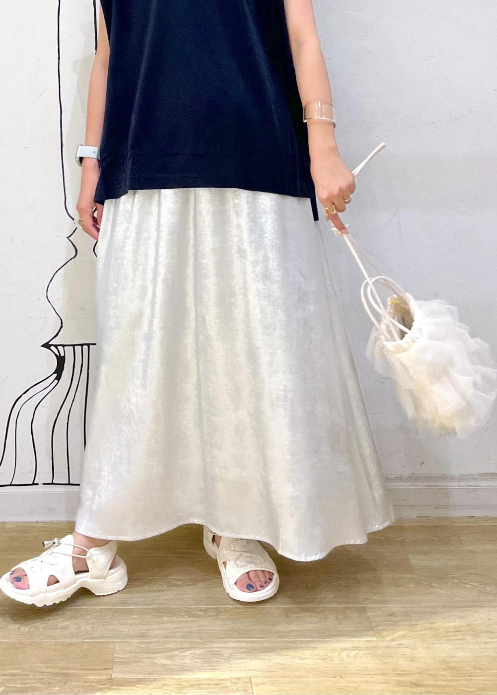 シルバー系のスカート、ブラック系のTシャツ/カットソー、ホワイト系のサンダルを着用したレディースの夏コーディネートの6枚目の写真