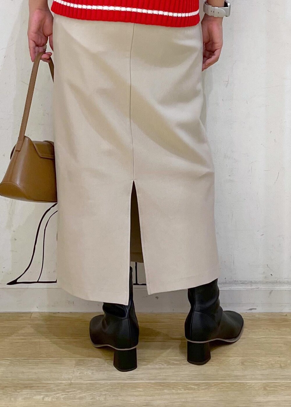 ベージュ系のスカート、レッド系のニット/セーター、ブラック系のブーツを着用したレディースの秋コーディネートの8枚目の写真