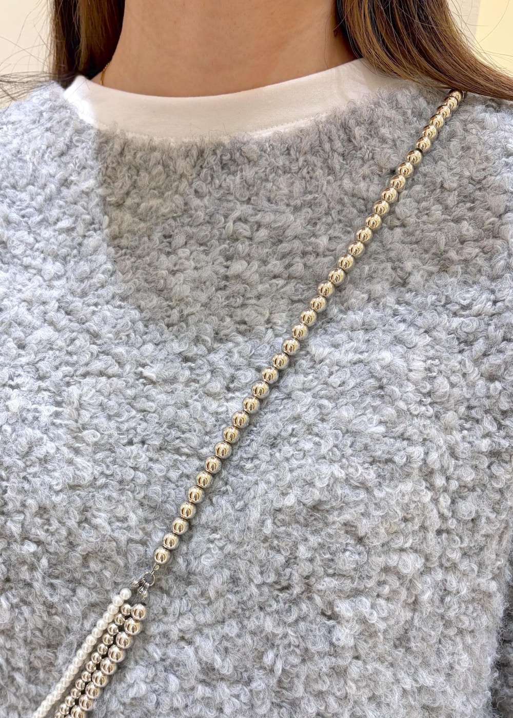 ブラック系のデニムパンツ、ブラウン系のブーツ、グレー系のニット/セーターを着用したレディースの冬コーディネートの5枚目の写真