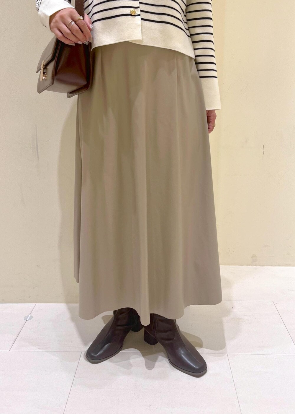 レッド系のショルダーバッグ、ベージュ系のスカート、ホワイト系のカーディガン/ボレロを着用したレディースの秋コーディネートの9枚目の写真