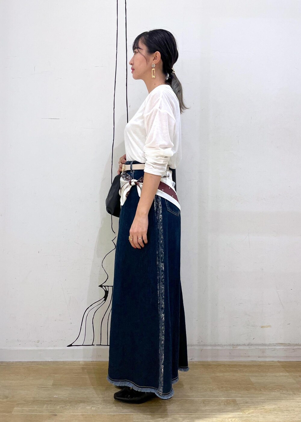 ブラック系のパンプス、ブラック系のトートバッグ、ブルー系のデニムスカートを着用したレディースの秋コーディネートの3枚目の写真