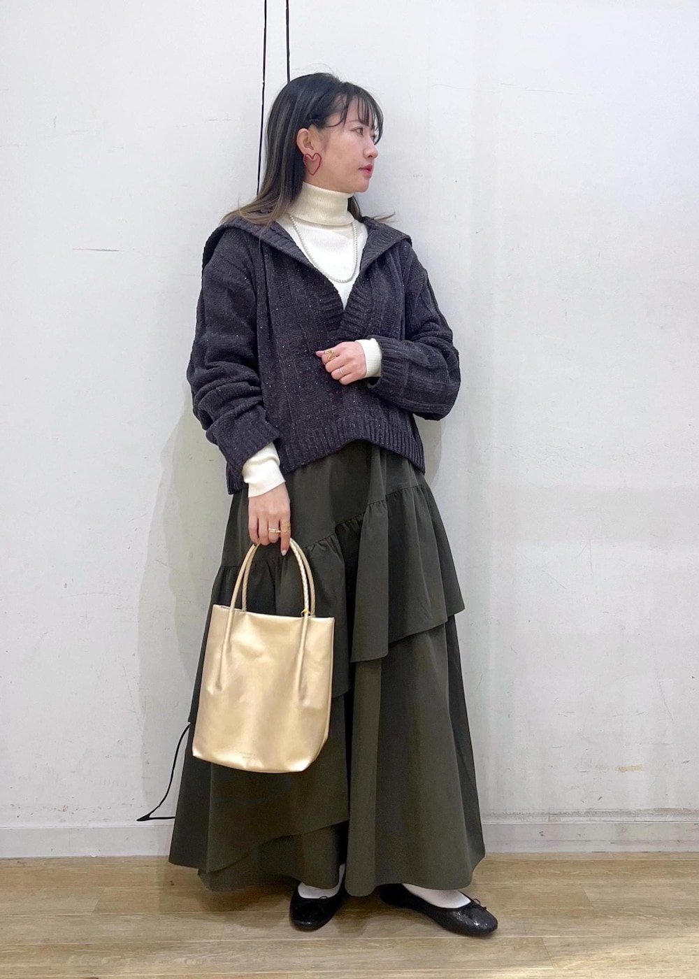 ホワイト系のニット/セーター、ブラック系のバレエシューズ、グリーン系のスカートを着用したレディースの冬コーディネートの2枚目の写真