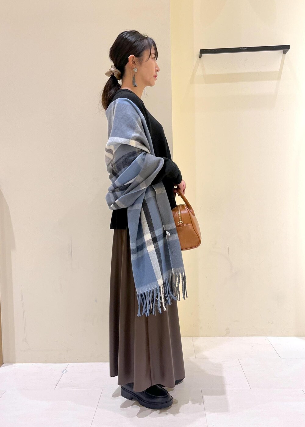 ブラウン系のスカート、ブラウン系のボストンバッグ、ブラック系のニット/セーターを着用したレディースの秋コーディネートの2枚目の写真