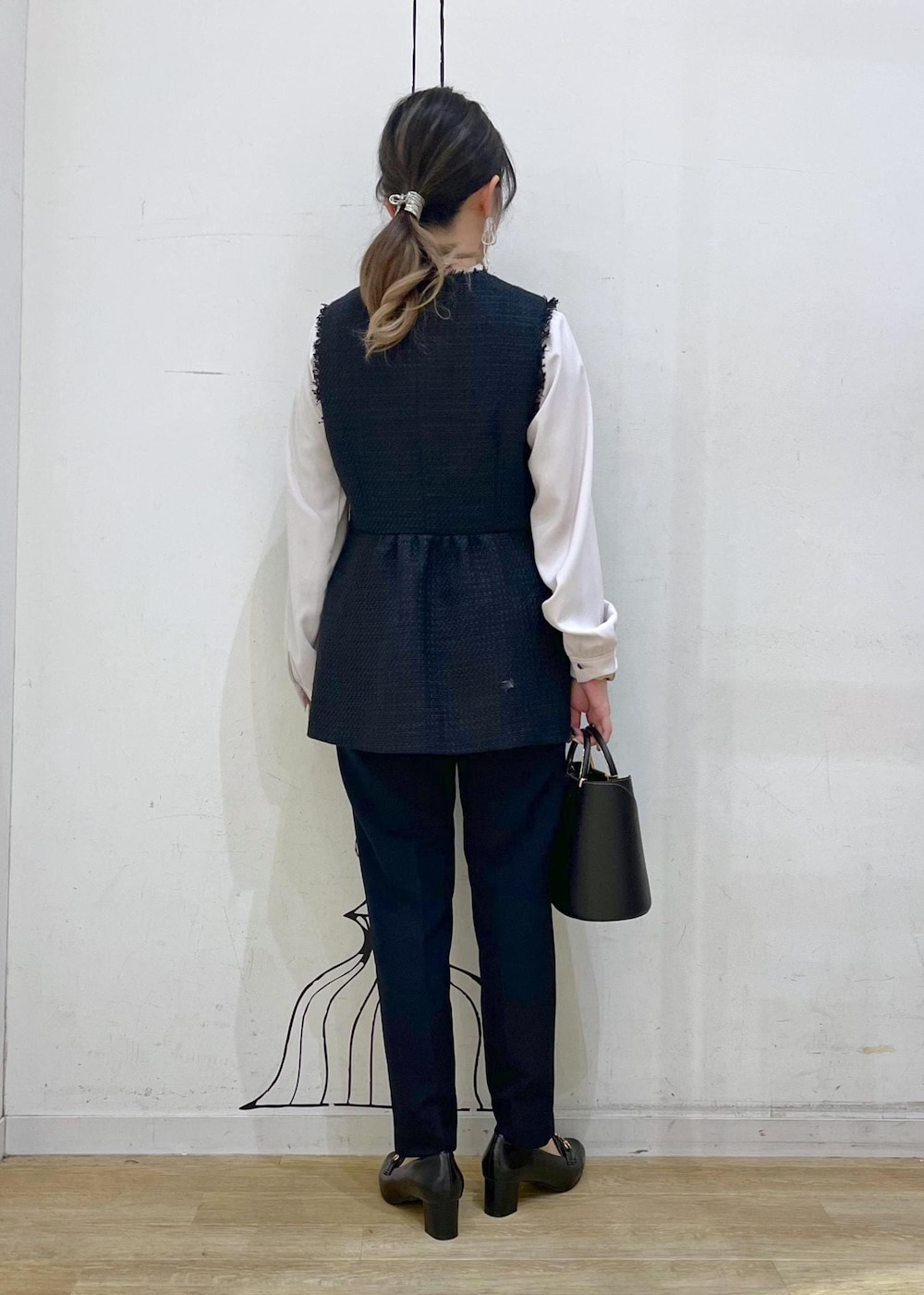 ブラック系のローファー、ブラック系のショルダーバッグ、ブルー系のベストを着用したレディースの冬コーディネートの4枚目の写真