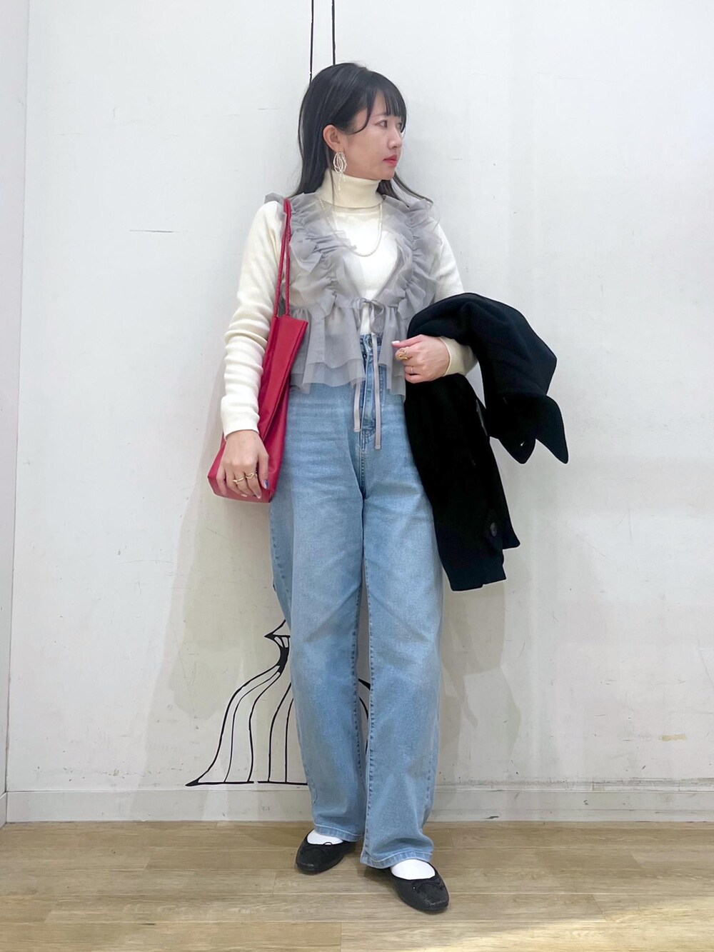 ブルー系のデニムパンツ、レッド系のトートバッグ、ブラック系のその他アウターを着用したレディースの冬コーディネートの4枚目の写真