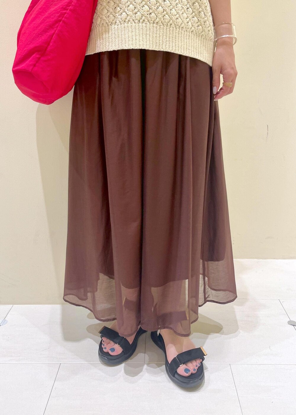 ブラック系のサンダル、ブラウン系のスカート、ベージュ系のベストを着用したレディースの夏コーディネートの9枚目の写真