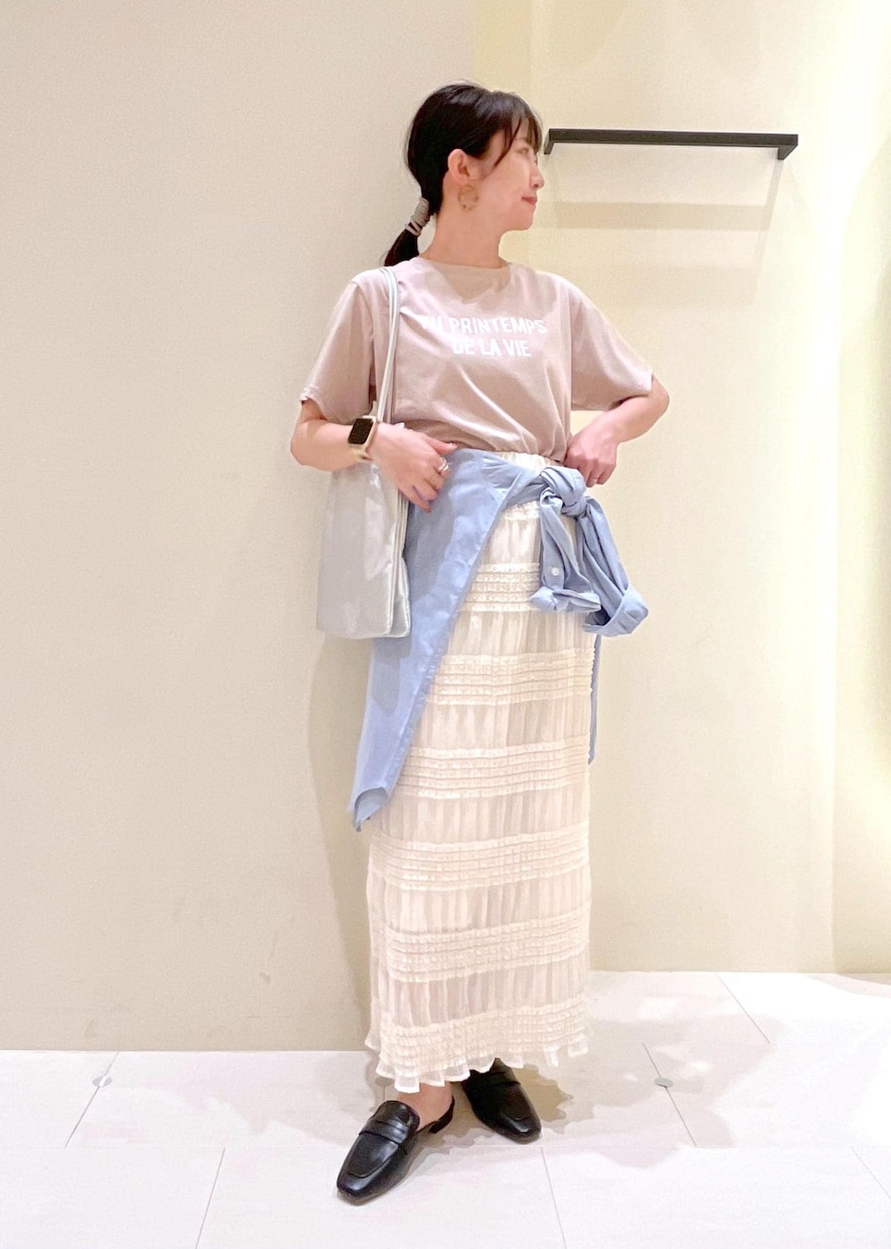 シルバー系のトートバッグ、ブラック系のローファー、ベージュ系のTシャツ/カットソーを着用したレディースの春コーディネートの2枚目の写真