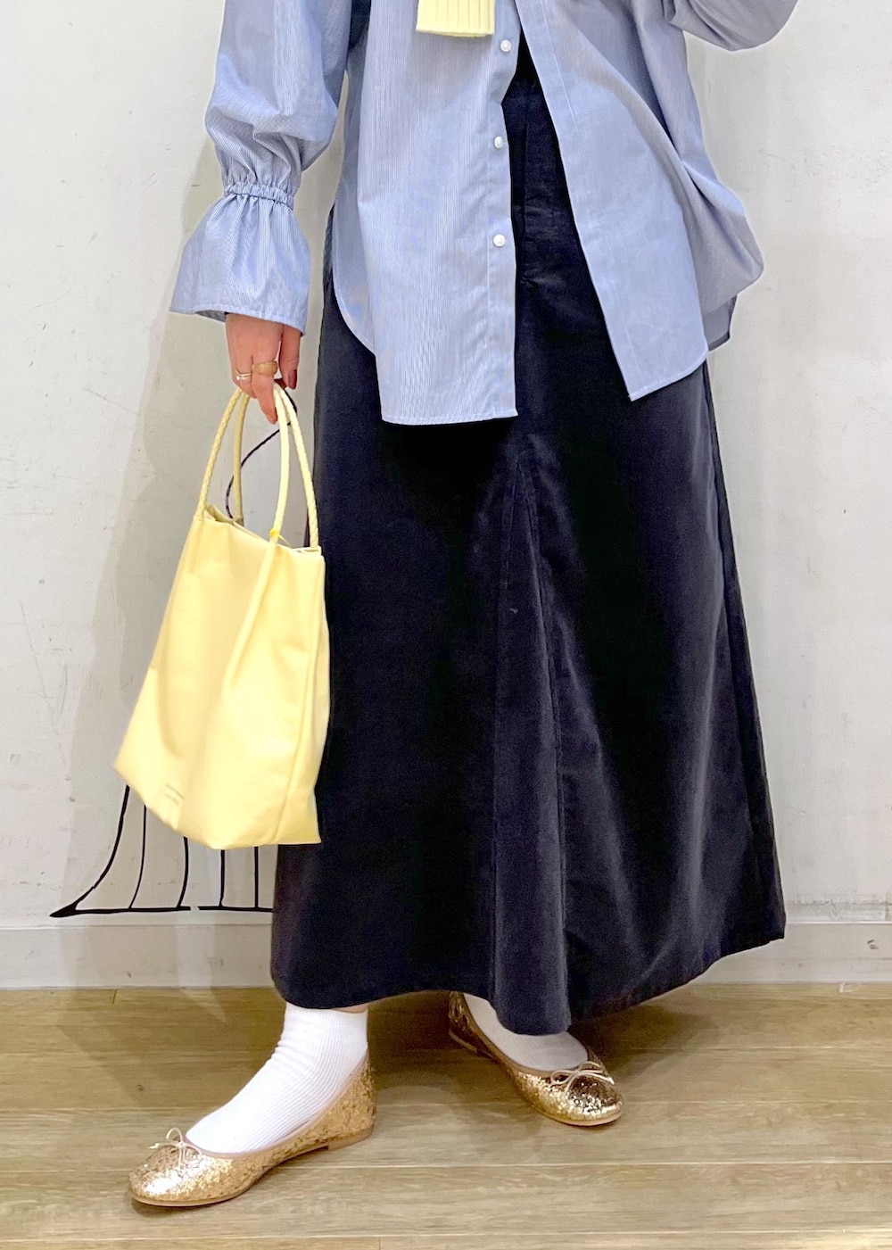 イエロー系のトートバッグ、グレー系のスカート、ブルー系のシャツ/ブラウスを着用したレディースの冬コーディネートの6枚目の写真