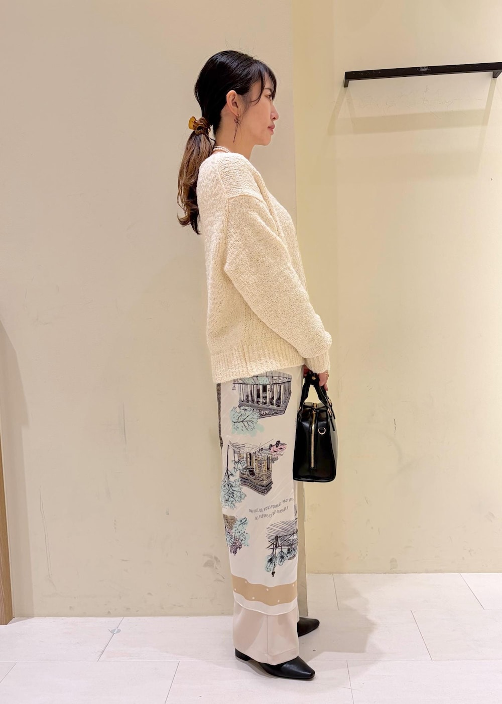 ブラック系のボストンバッグ、ベージュ系のその他パンツ、ホワイト系のニット/セーターを着用したレディースの冬コーディネートの2枚目の写真