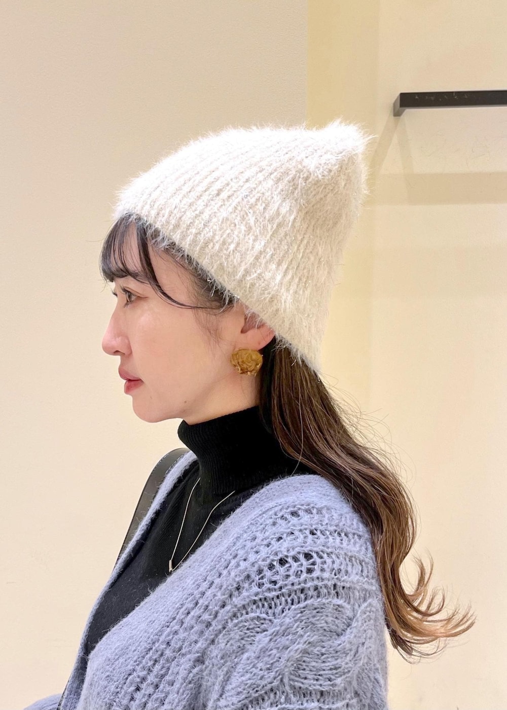 ブラック系のショルダーバッグ、ブラック系のニット/セーター、グレー系のスラックスを着用したレディースの秋コーディネートの5枚目の写真