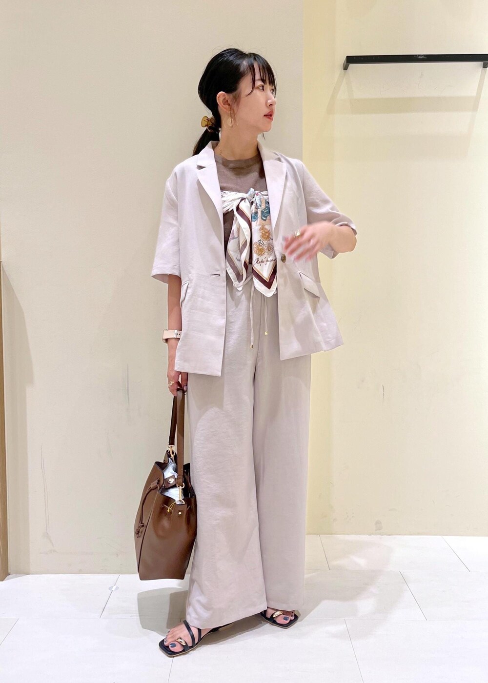 ベージュ系のテーラードジャケット、その他のニット/セーター、ブラウン系のショルダーバッグを着用したレディースの秋コーディネートの2枚目の写真