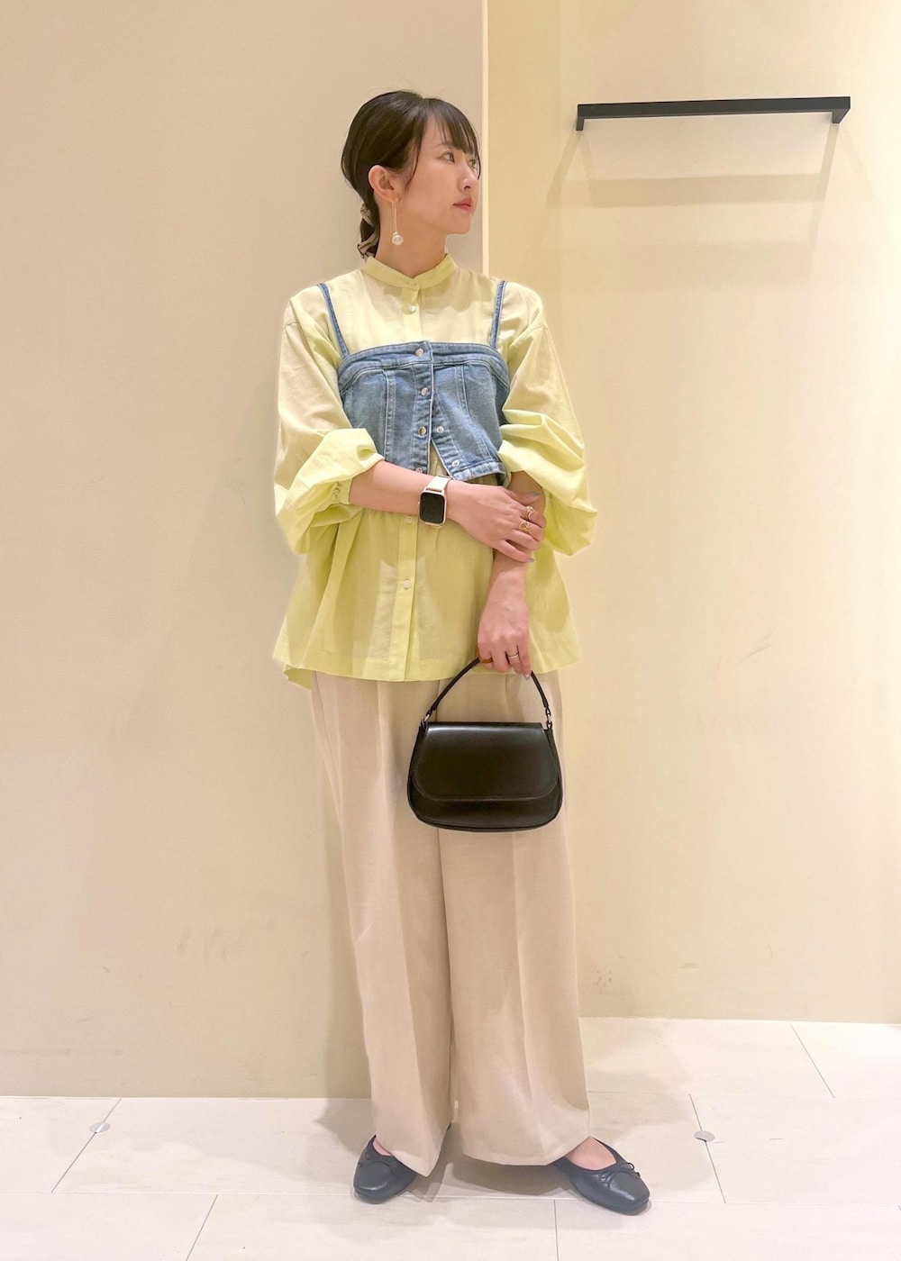 ブラック系のハンドバッグ、ブルー系のベスト、イエロー系のシャツ/ブラウスを着用したレディースの春コーディネートの3枚目の写真