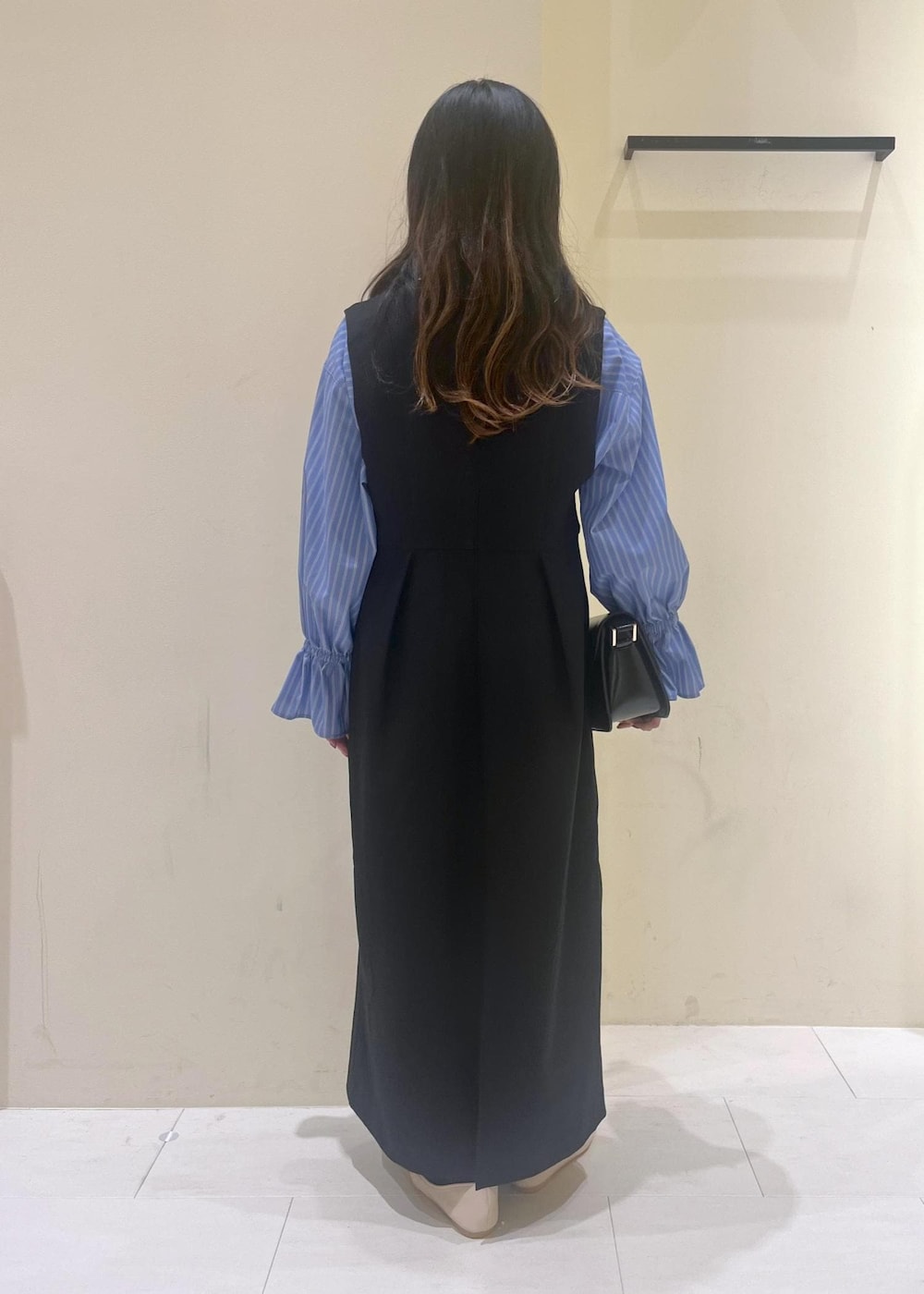 ホワイト系のバレエシューズ、ブラック系のショルダーバッグ、ブラック系のジャンパースカートを着用したレディースの冬コーディネートの4枚目の写真