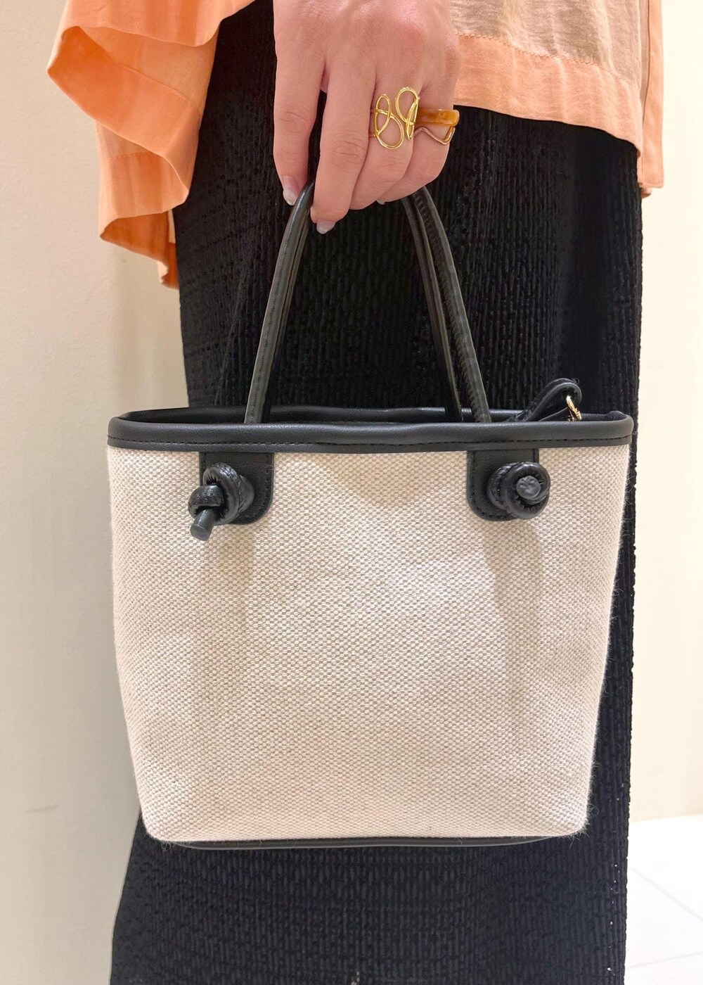 オレンジ系のシャツ/ブラウス、シルバー系のパンプス、ブラック系のトートバッグを着用したレディースの夏コーディネートの9枚目の写真