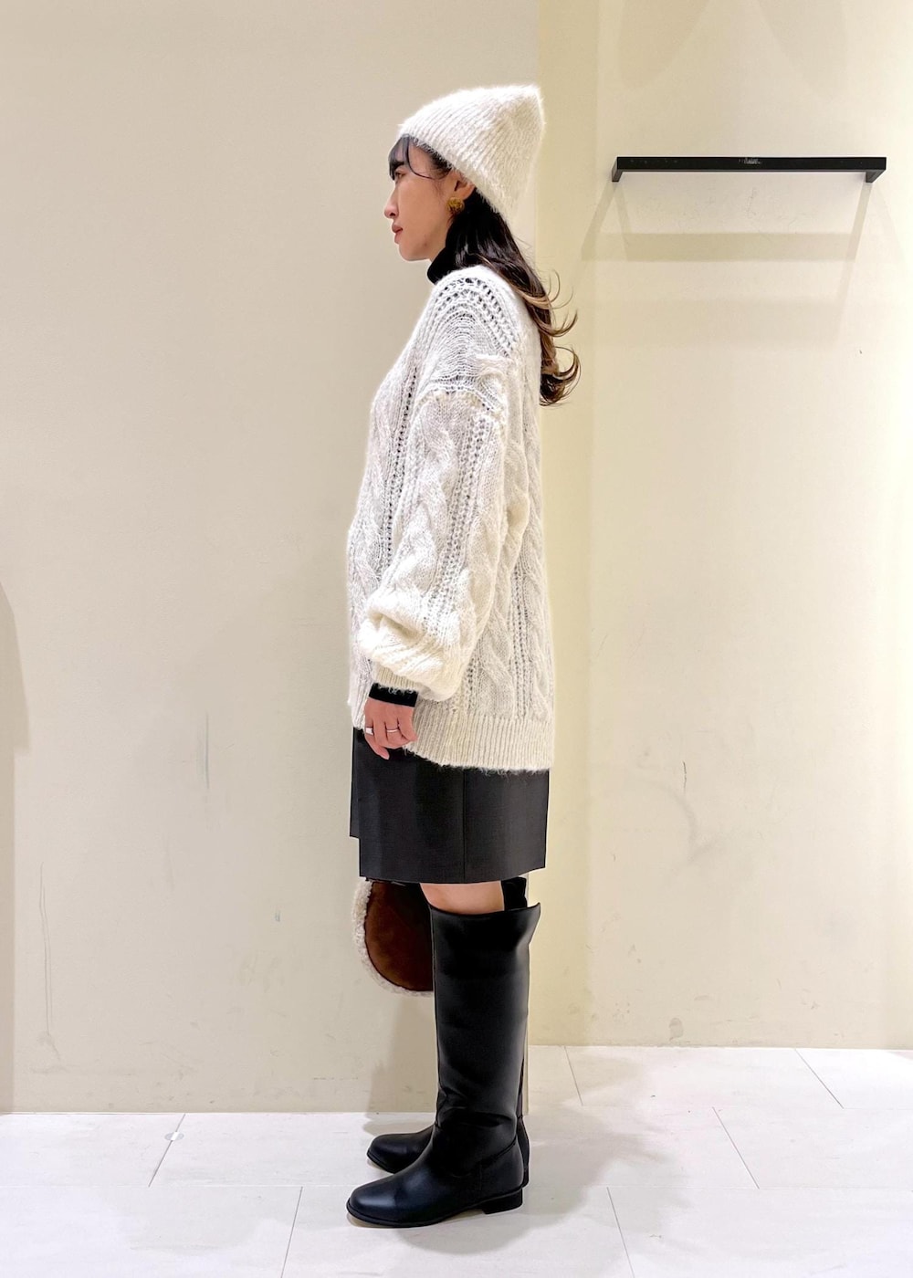 ブラック系のニット/セーター、ブラック系のブーツ、ブラウン系のショルダーバッグを着用したレディースの秋コーディネートの2枚目の写真