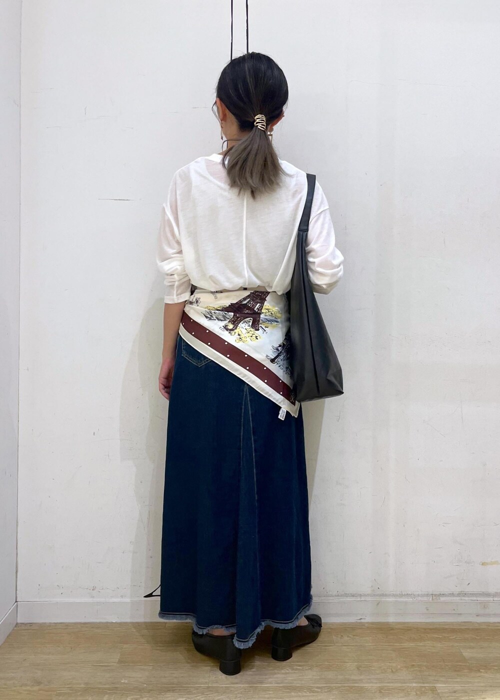 ブラック系のパンプス、ブラック系のトートバッグ、ブルー系のデニムスカートを着用したレディースの秋コーディネートの4枚目の写真