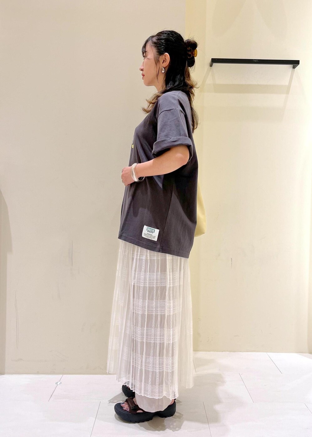 イエロー系のトートバッグ、ホワイト系のスカート、ベージュ系のその他パンツを着用したレディースの夏コーディネートの5枚目の写真