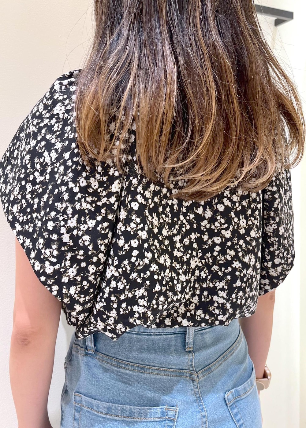 ブルー系のデニムパンツ、ブラック系のハンドバッグ、シルバー系のサンダルを着用したレディースの夏コーディネートの6枚目の写真