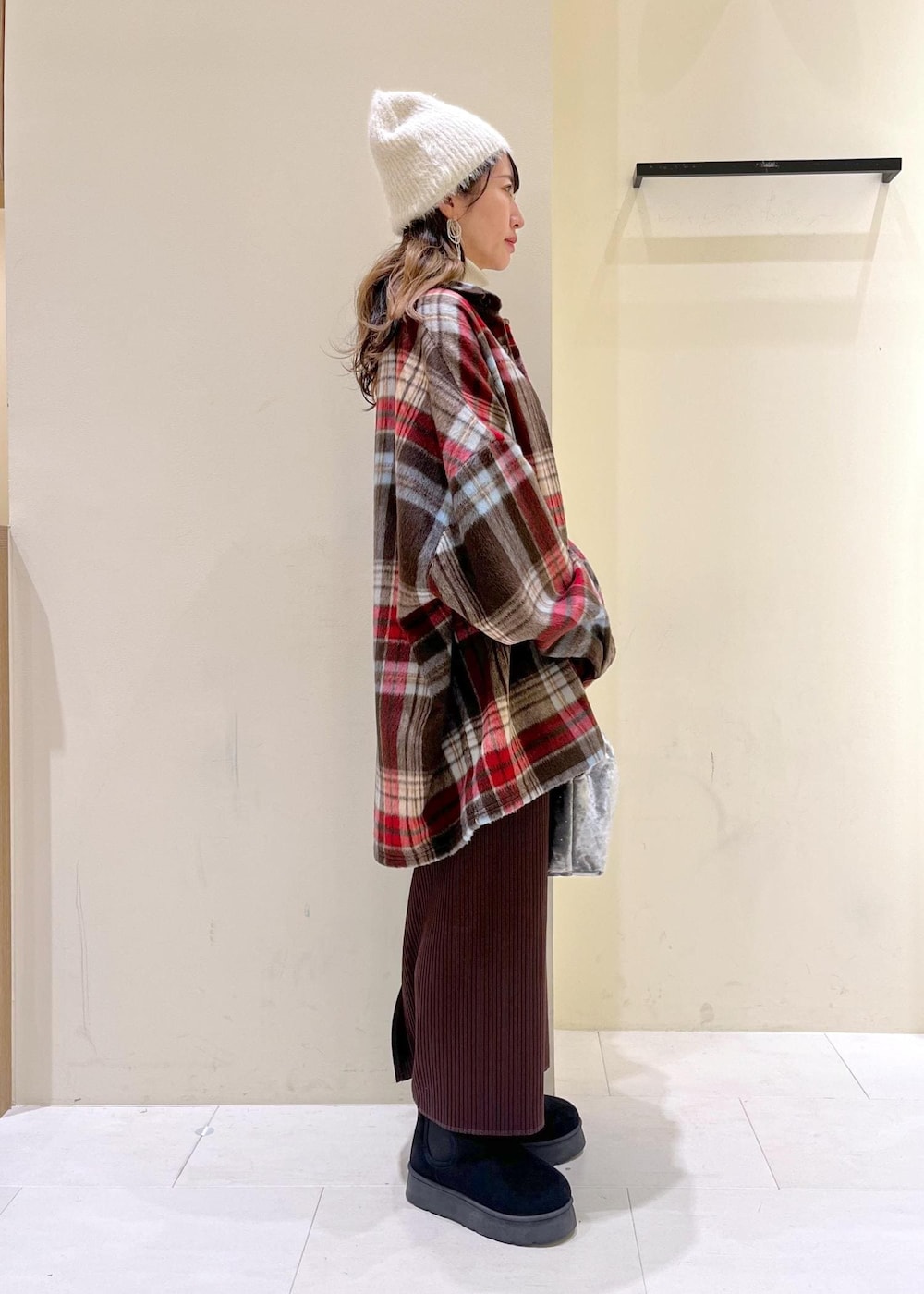 ブラック系のブーツ、ホワイト系のニット/セーター、シルバー系のハンドバッグを着用したレディースの冬コーディネートの2枚目の写真