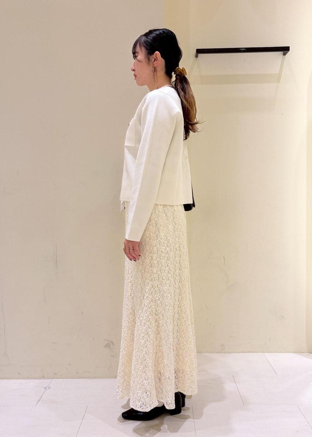 ブラック系のショルダーバッグ、ホワイト系のカーディガン/ボレロ、ホワイト系のスカートを着用したレディースの冬コーディネートの4枚目の写真