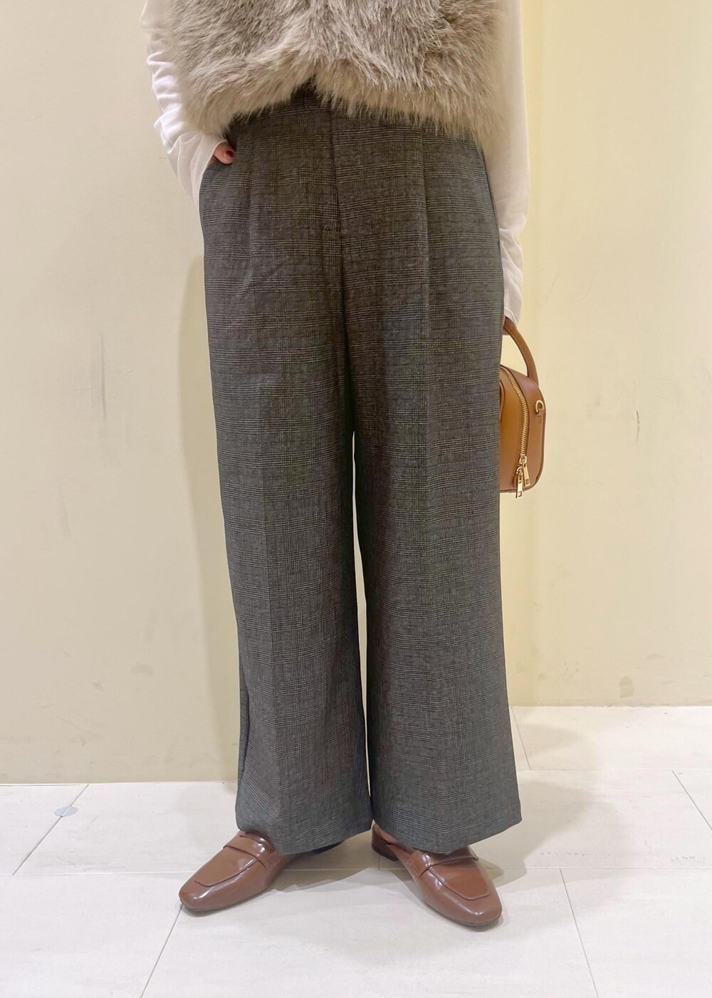 ブラウン系のベスト、ホワイト系のTシャツ/カットソー、グレー系のスラックスを着用したレディースの秋コーディネートの7枚目の写真